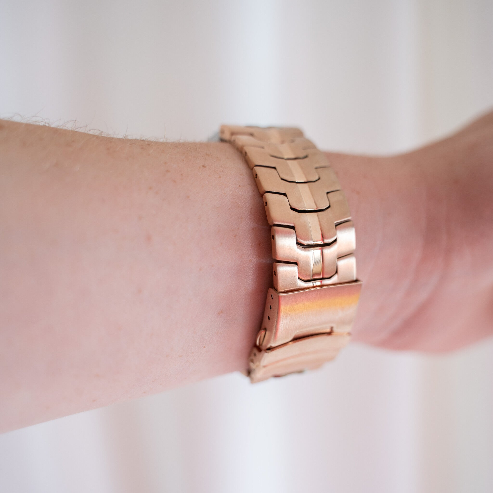 Ein Arm mit einer goldenen Uhr. Die Uhr befindet sich am Handgelenk, der Hintergrund ist weiß.