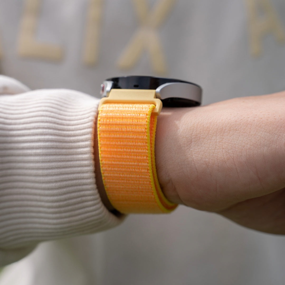 Handgelenk mit Smartwatch. Die Uhr hat ein orangefarbenes Armband. Der Hintergrund ist eine verschwommene Person.