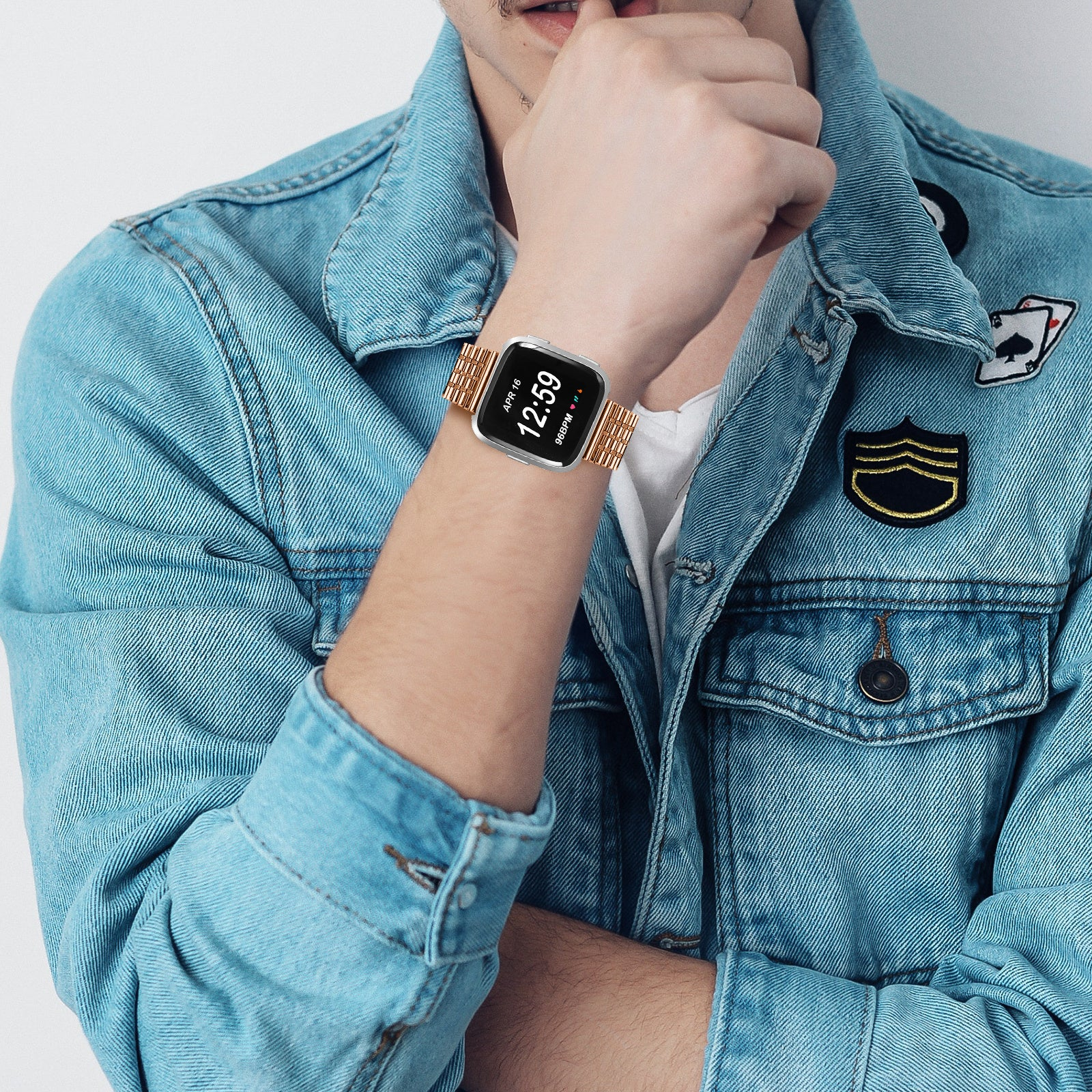 Eine Person trägt eine Jeansjacke und eine Uhr mit goldenem Armband. Die Uhr zeigt die Zeit: 12:59.