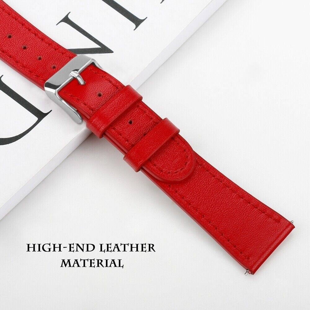 Nahaufnahme eines roten Leder-Armbandes mit silberner Schnalle. Der Riemen liegt auf einer weißen Oberfläche mit schwarzen Buchstaben.