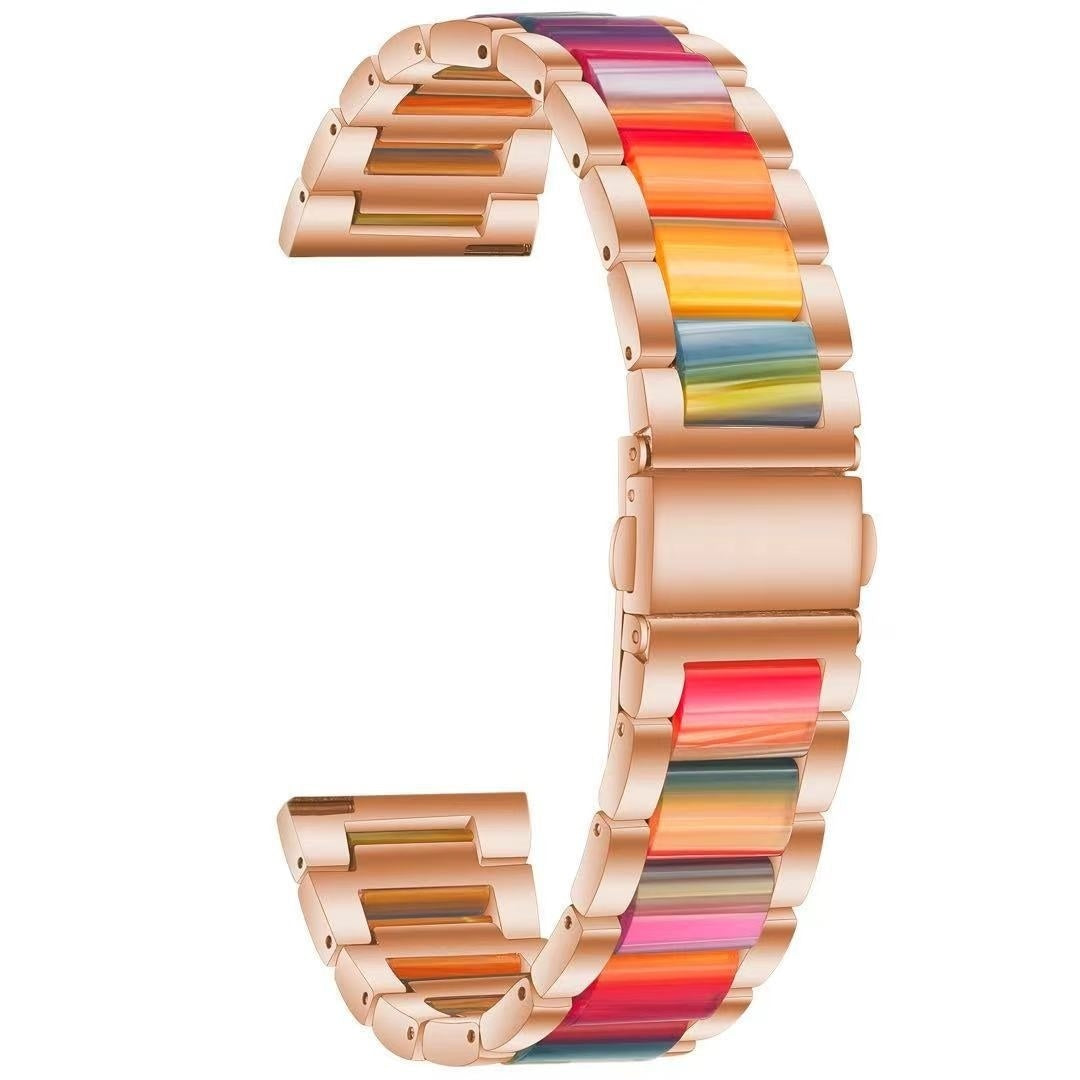 Ein Uhrenarmband mit roségoldenen Gliedern und bunten Segmenten in Rot, Orange, Gelb, Grün und Blau. Es ist vor weißem Hintergrund gebogen.