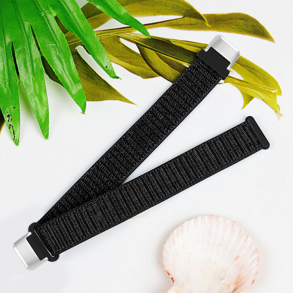 Schwarze Uhrenarmbänder auf weißem Untergrund mit grünen und gelben Blättern und einer Muschel. Die Armbänder haben silberne Verschlüsse.