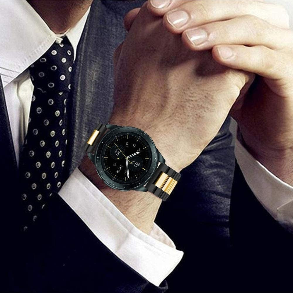 Ein Mann im Anzug mit einer schwarzen Uhr mit goldenen Akzenten. Die Uhr ist an seinem linken Handgelenk.