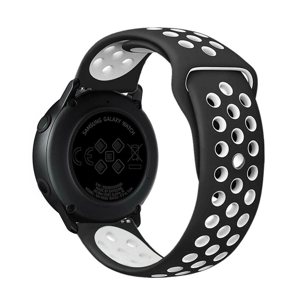 Eine schwarze Samsung Galaxy Watch mit einem schwarz-weißen perforierten Armband. Die Rückseite der Uhr zeigt Informationen und Zertifizierungen.
