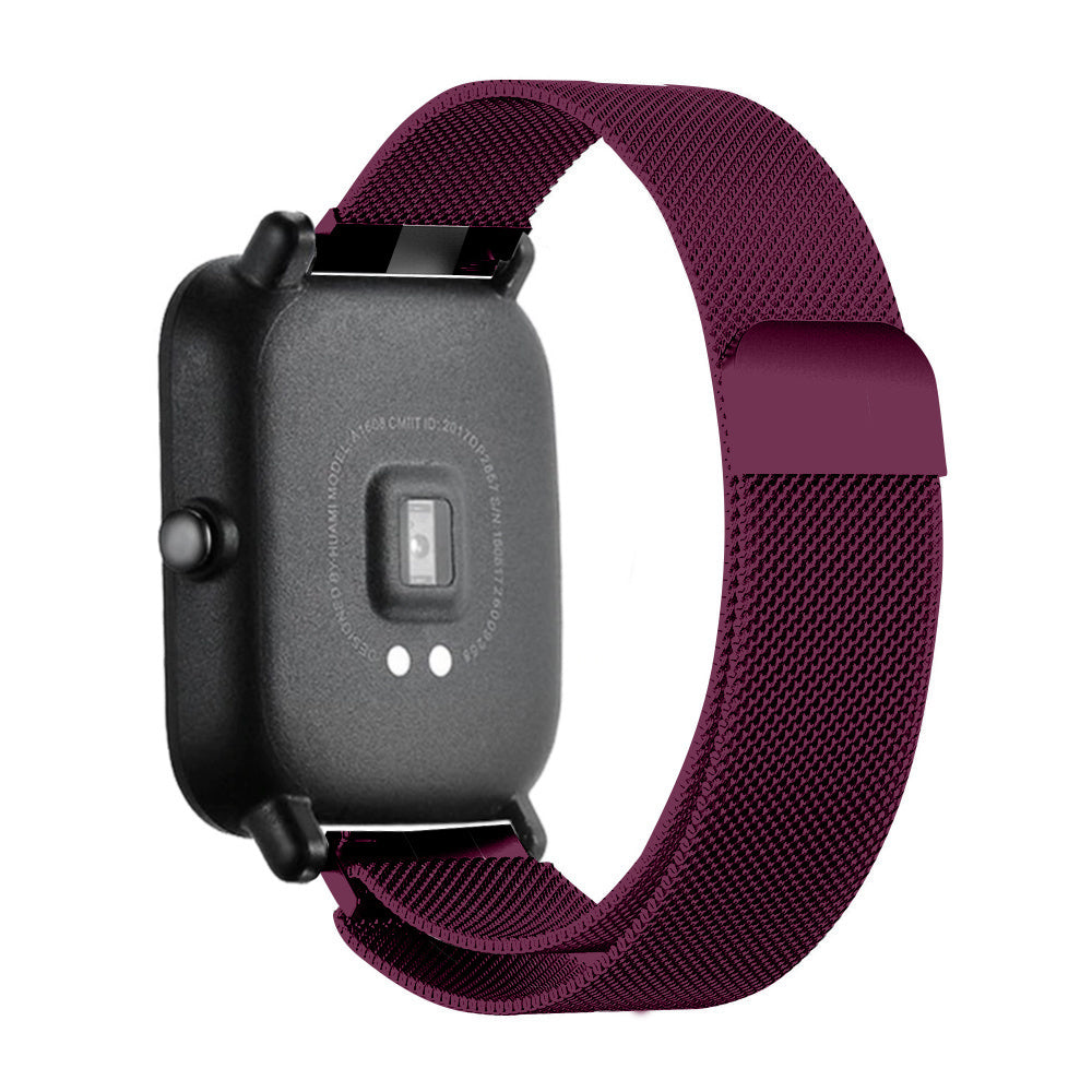 Eine schwarze Smartwatch mit einem dunkelroten Mesh-Armband. Die Uhr ist angewinkelt und zeigt die Rückseite mit Sensoren und Text. Weißer Hintergrund.