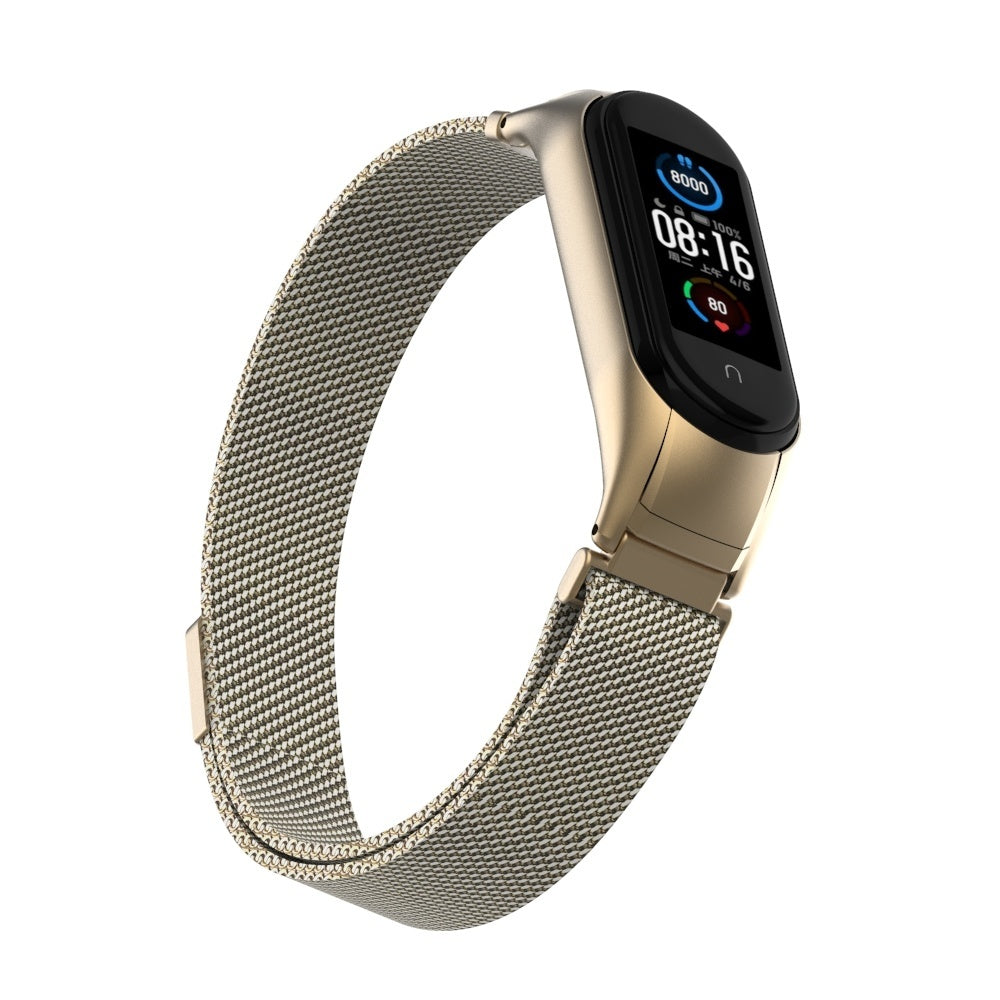 Eine goldene Smartwatch mit schwarzem Display, das Zeit und Gesundheitsdaten anzeigt. Das Armband ist aus Metallgeflecht. Weißer Hintergrund.