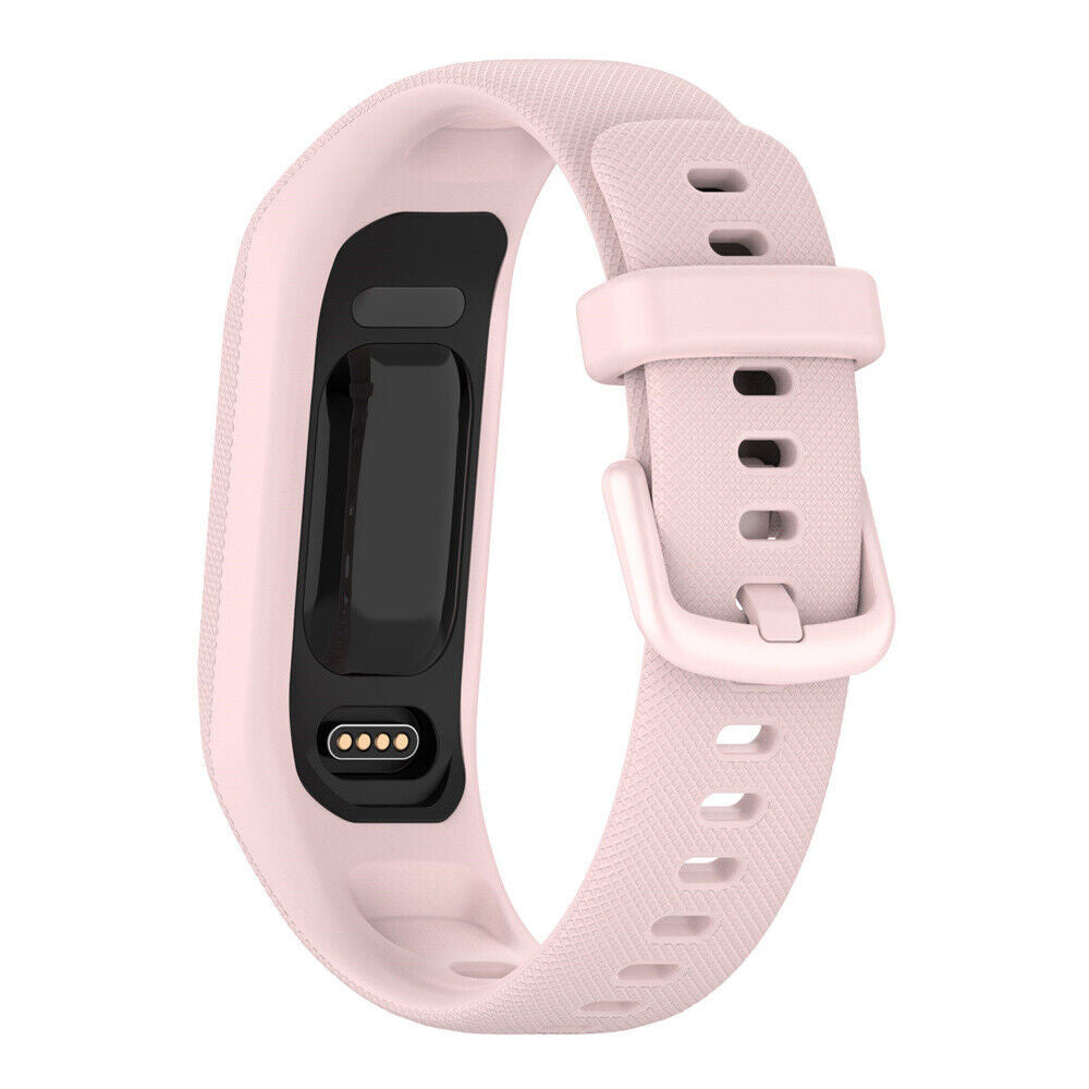 Ein hellrosa Fitness-Tracker mit schwarzem Display. Das Band hat einen Schnallenverschluss. Unten sind vier Ladepunkte sichtbar.