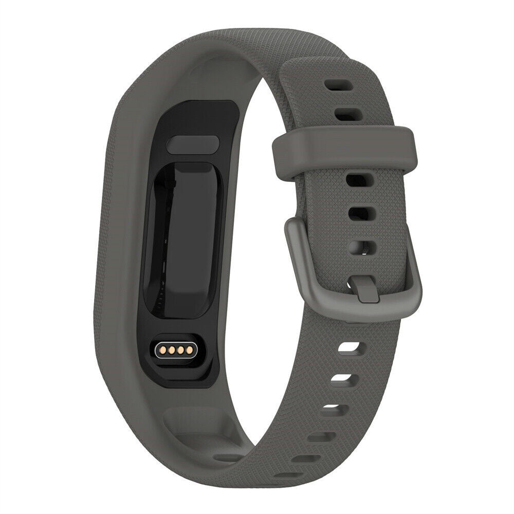 Ein grauer Fitnesstracker auf weißem Hintergrund. Er hat einen rechteckigen Bildschirm, einen Ladeanschluss und ein Armband.