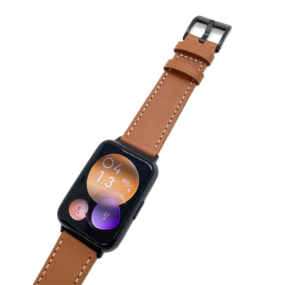 Eine schwarze Smartwatch mit braunem Lederarmband. Der Bildschirm zeigt Datum und Uhrzeit mit zwei runden Widgets. Isoliert auf Weiß.