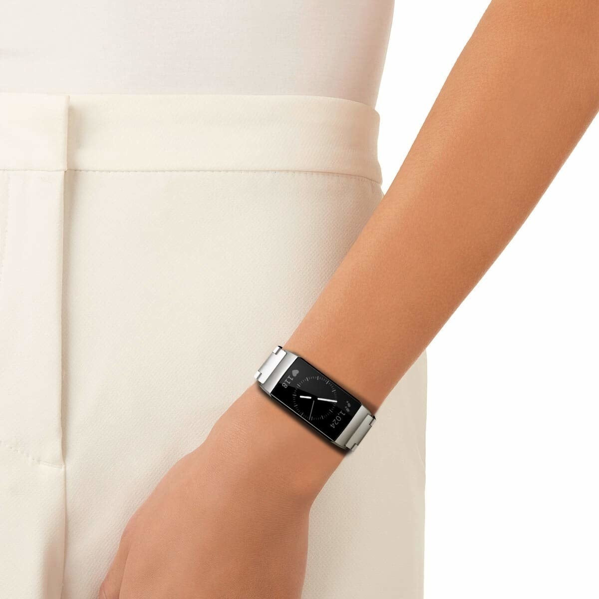 Arm einer Person mit einer silbernen Smartwatch mit schwarzem Bildschirm. Die Person trägt ein weißes Outfit. Die Uhr zeigt Daten.