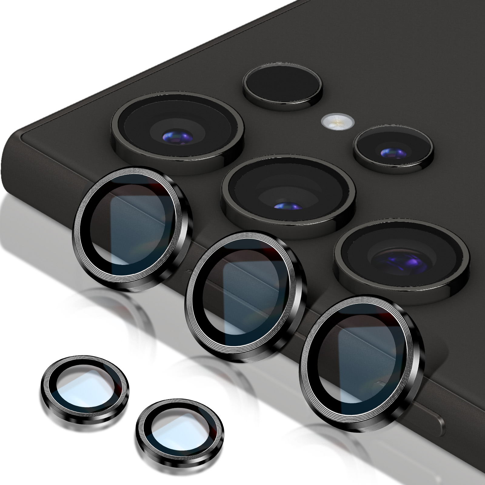 Uno smartphone con più obiettivi della fotocamera. Diversi proteggi-lenti sono posizionati vicino al telefono. Lo sfondo è bianco.