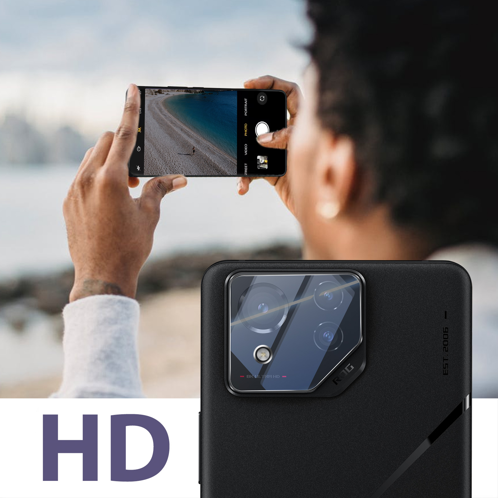 Una persona tiene in mano un telefono, fotografando una scena sulla spiaggia. La fotocamera del telefono è accesa. È visibile anche una custodia per telefono.