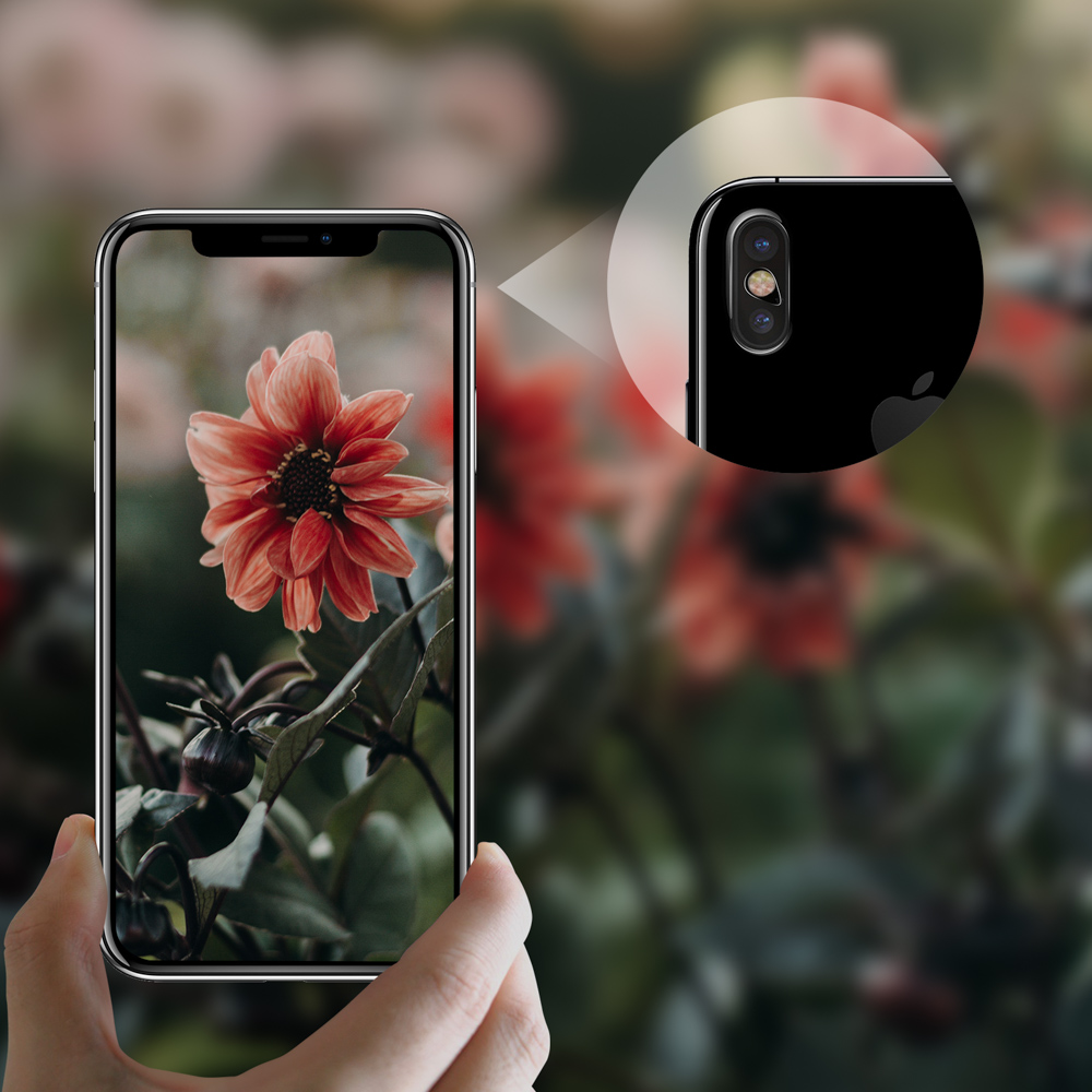 Mano che tiene un telefono con un fiore. Primo piano della fotocamera del telefono. Sfondo con fiori sfocati.