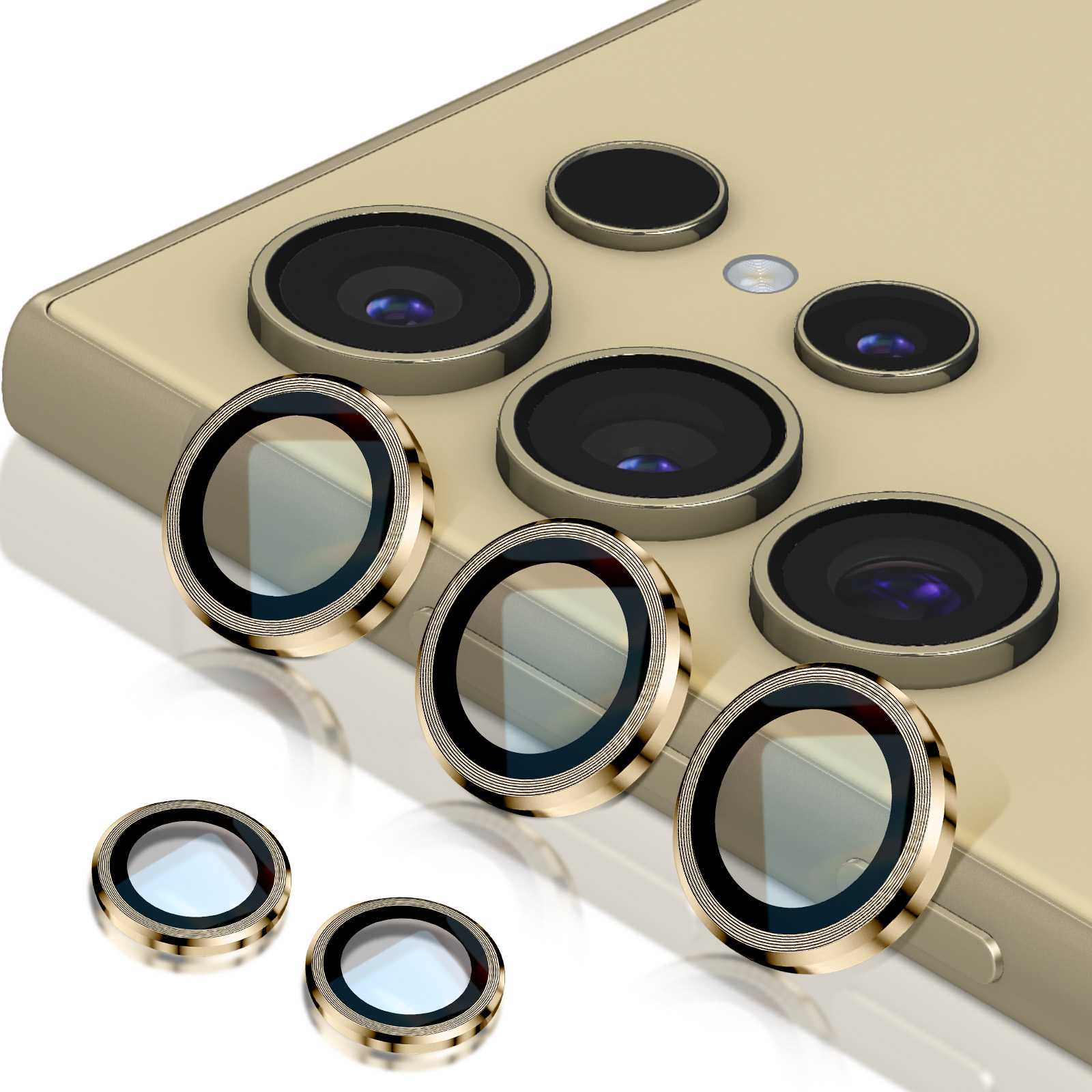 Un teléfono inteligente dorado con lentes de cámara y varios protectores de lentes frente al teléfono, todos dorados y negros.