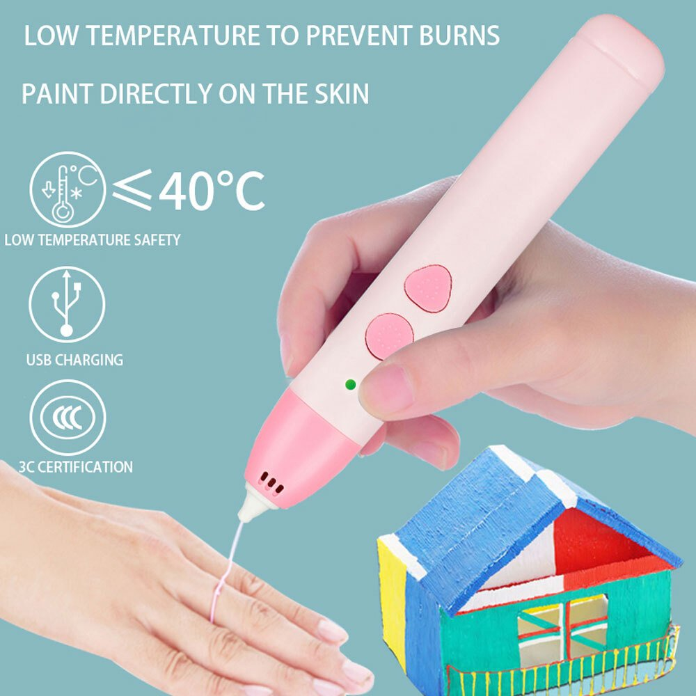 Una mano sostiene un bolígrafo rosa dibujando en un dedo. Una pequeña casa está en el fondo. El texto indica seguridad a baja temperatura y carga USB.