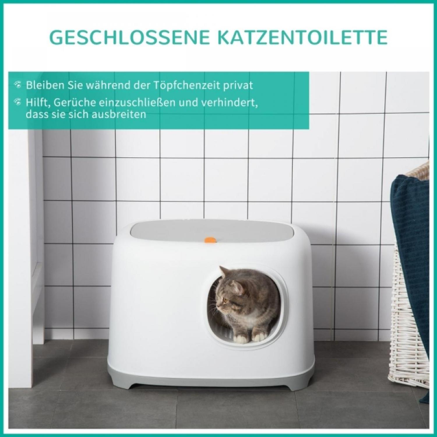 Eine Katze sitzt in einer geschlossenen, weißen Katzentoilette. Die Box befindet sich in einem Badezimmer mit gefliesten Wänden. Rechts ist ein Handtuchhalter.