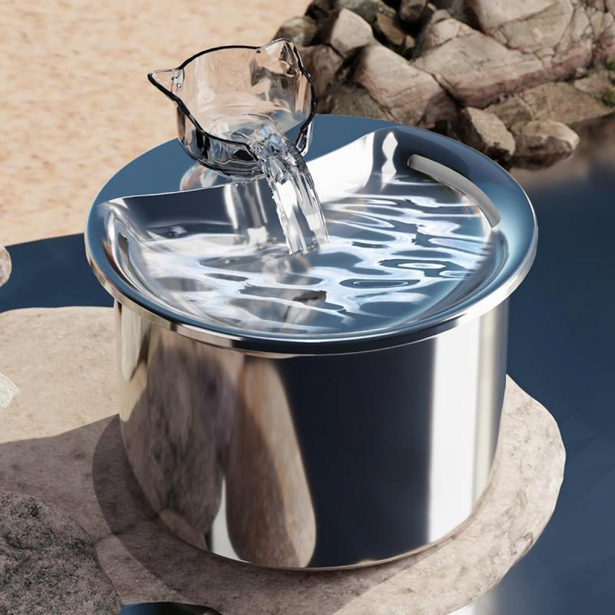Ein Edelstahl-Haustier-Wasserbrunnen, bei dem Wasser aus einem katzenförmigen Spender in die Schüssel fließt. Der Hintergrund zeigt Steine ​​und Wasser.