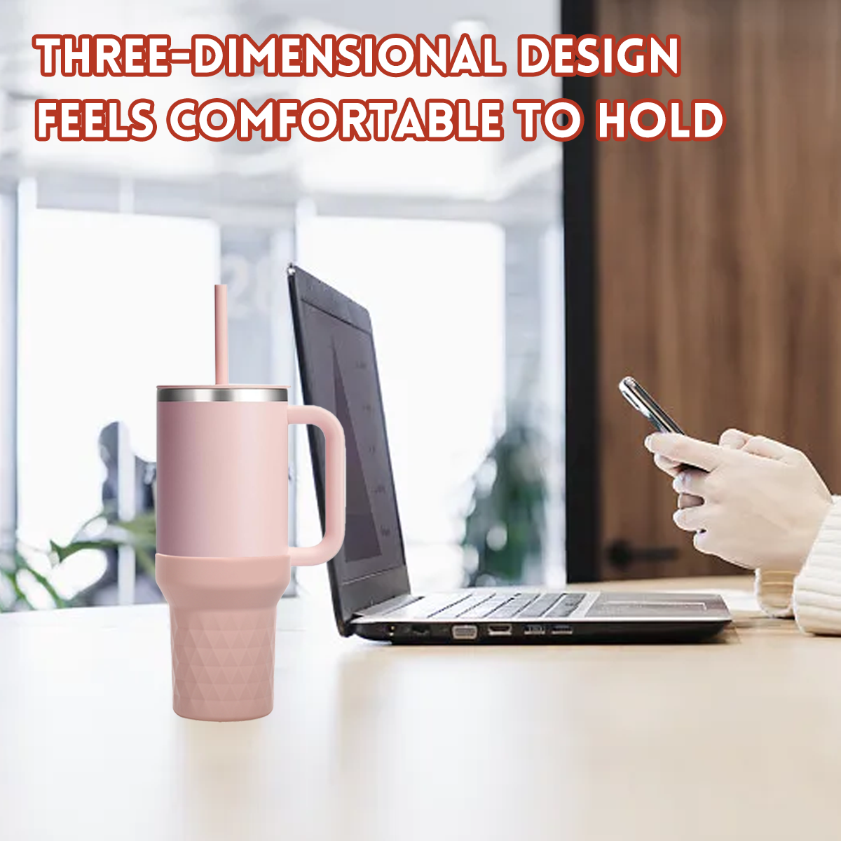 Rosa Becher mit Strohhalm steht auf einem Holztisch neben einem Laptop. Eine Hand hält ein Telefon. Text: 3D-Design fühlt sich angenehm an.