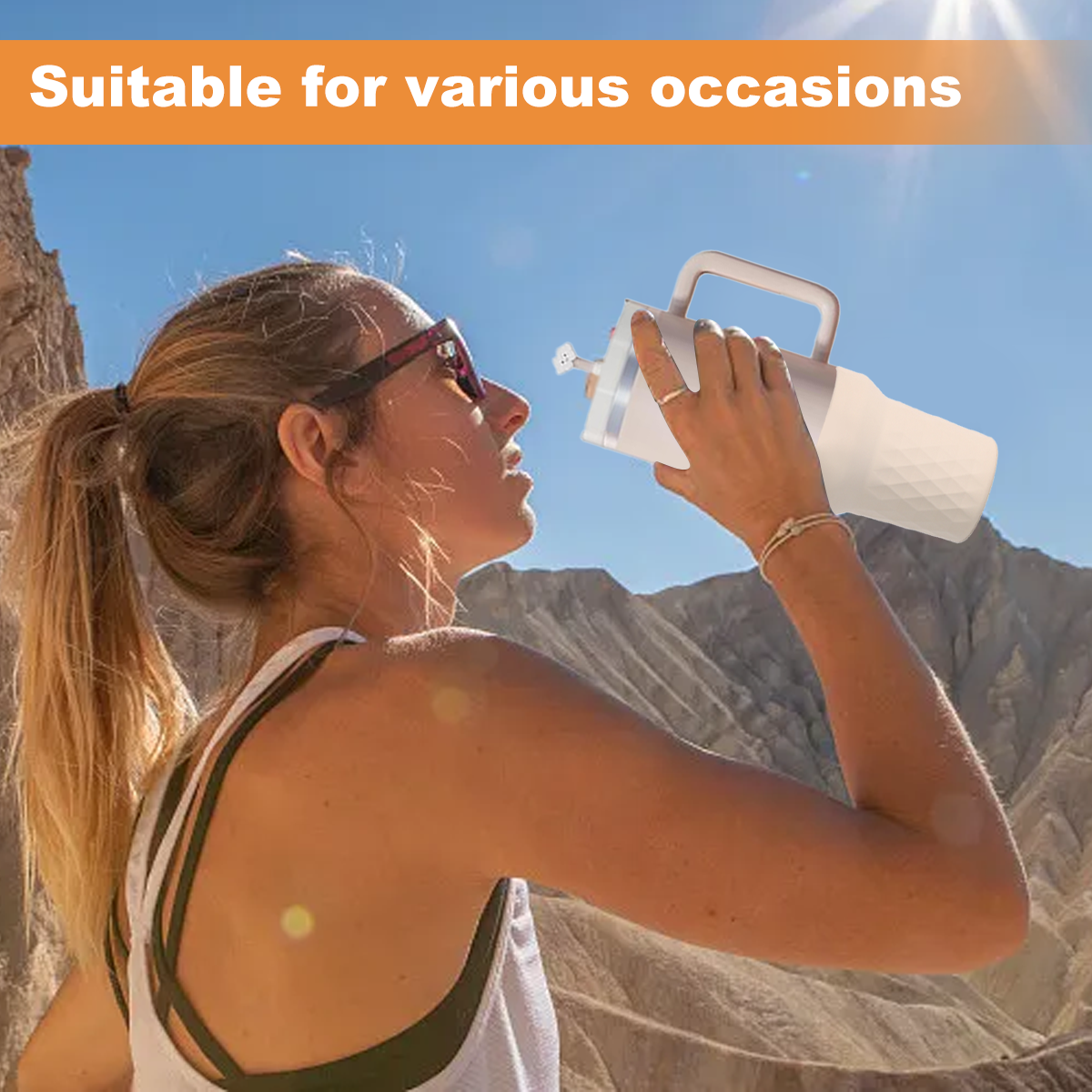 Eine Frau trinkt aus einer Wasserflasche in einer sonnigen Berglandschaft. Sie trägt eine Sonnenbrille und ein Tanktop. Die Flasche hat einen Griff.