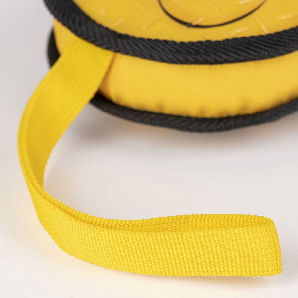 Primo piano di un oggetto giallo con un cinturino giallo. L'oggetto è rotondo con un bordo nero. Il cinturino è curvo verso il basso.