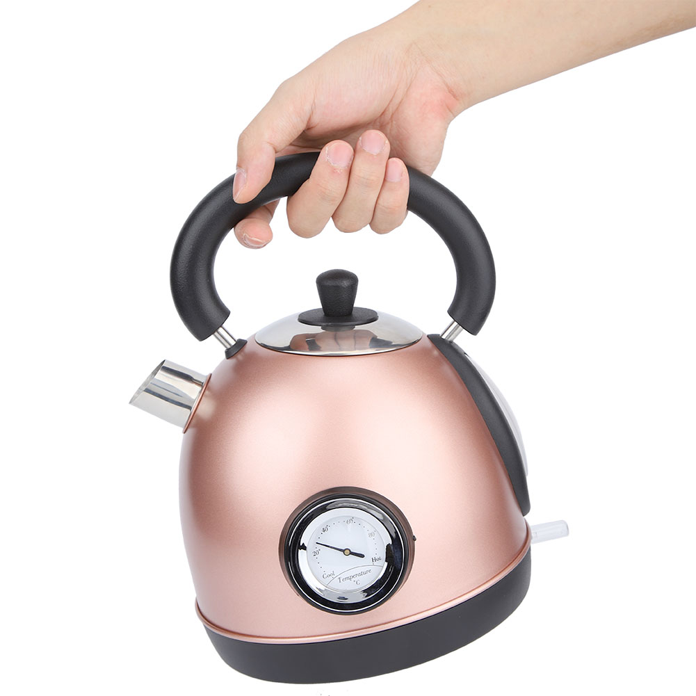 Eine Hand hält einen roségoldenen Wasserkocher mit schwarzem Griff und Sockel. Er hat ein Temperaturmessgerät und einen Ausguss.
