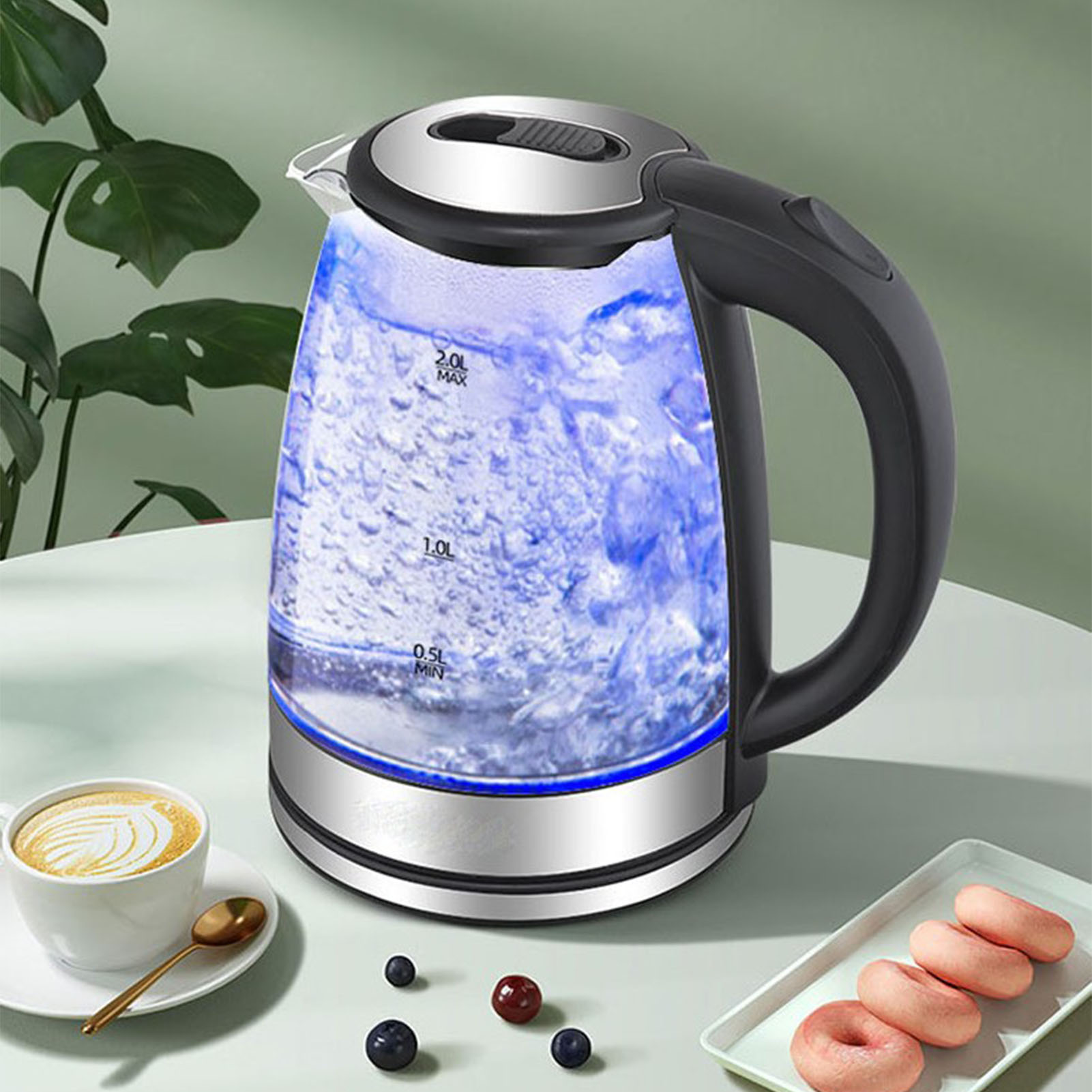 Elektrischer Wasserkocher mit kochendem Wasser, Kaffee, Donuts und Beeren auf einem Tisch. Grüne Pflanze im Hintergrund.