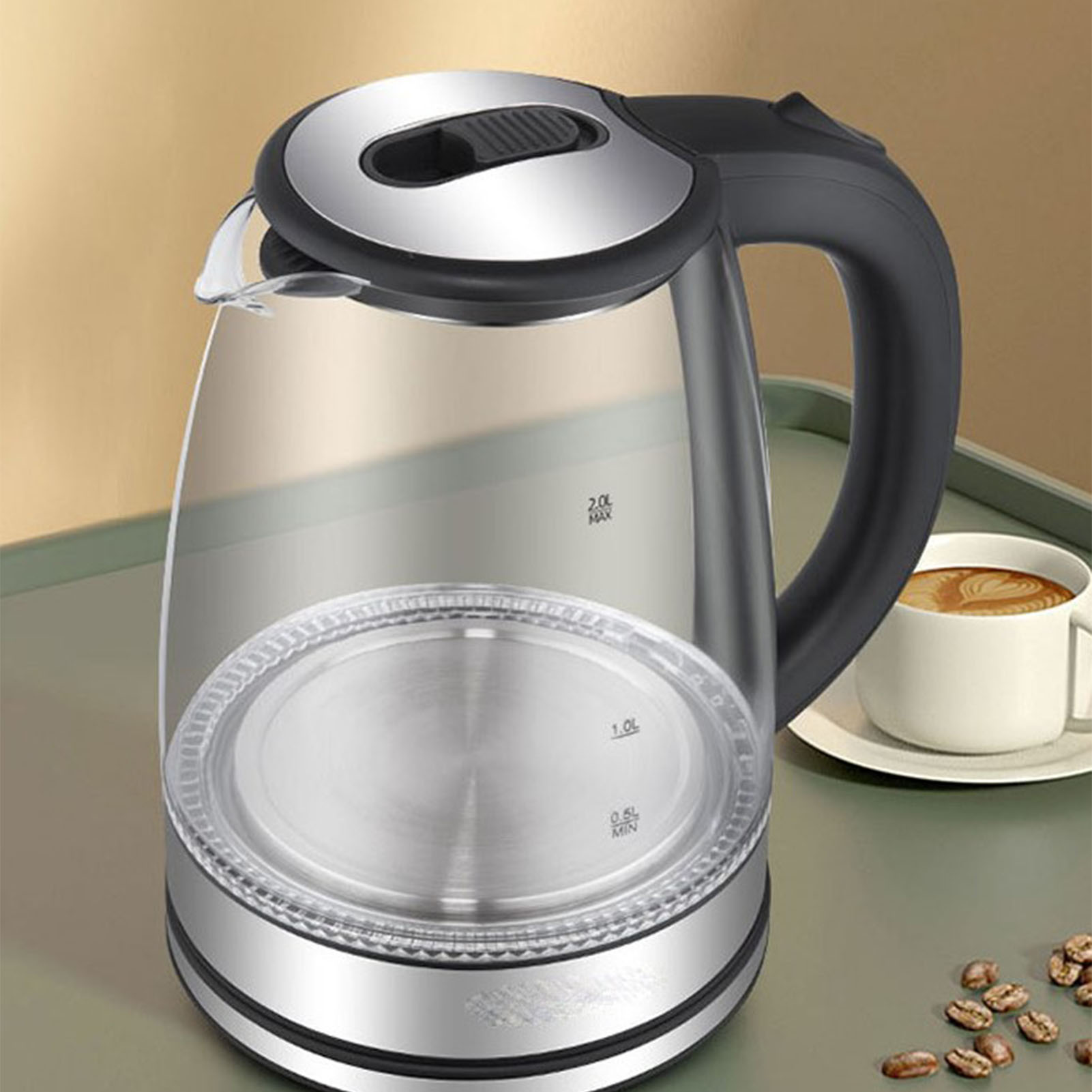 Ein elektrischer Glaskessel mit schwarzem Griff und Deckel, in der Nähe einer Tasse Kaffee und Kaffeebohnen.