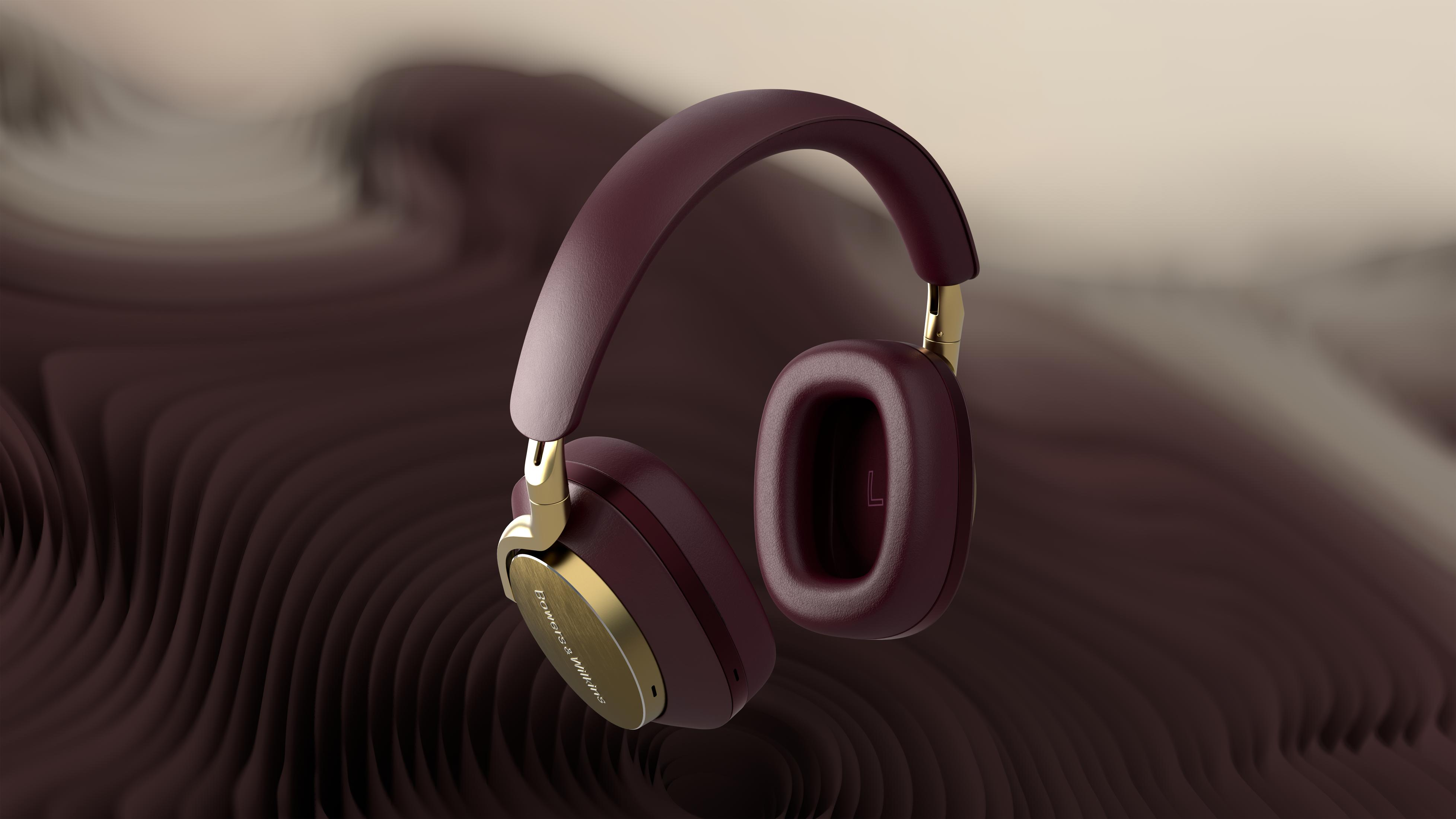 Bordowe słuchawki ze złotymi akcentami, unoszące się na tle brązowego tła.