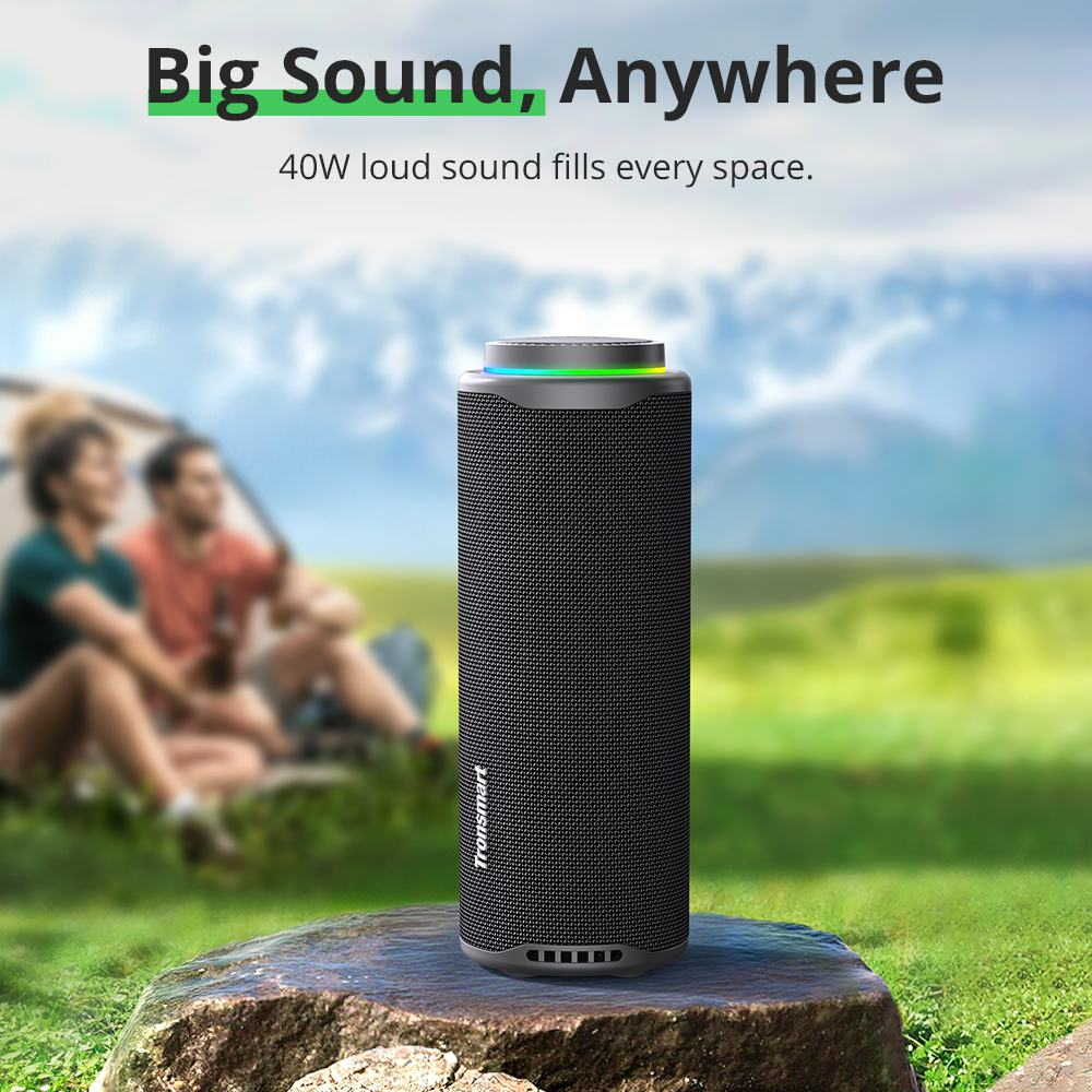 Czarny głośnik na skale. Rozmyte tło z namiotem i ludźmi. Tekst: 'Big Sound, Anywhere'.