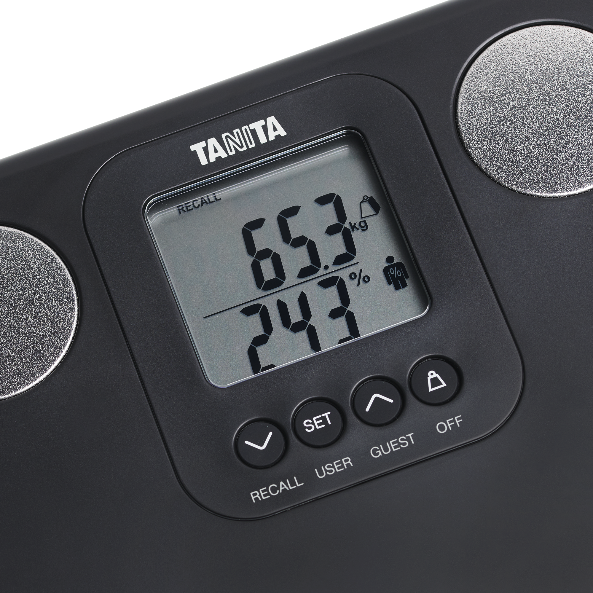 Een zwarte Tanita-weegschaal toont 65,3 kg en 24,3% op het scherm. Het heeft knoppen voor recall, gebruiker, gast en uit.