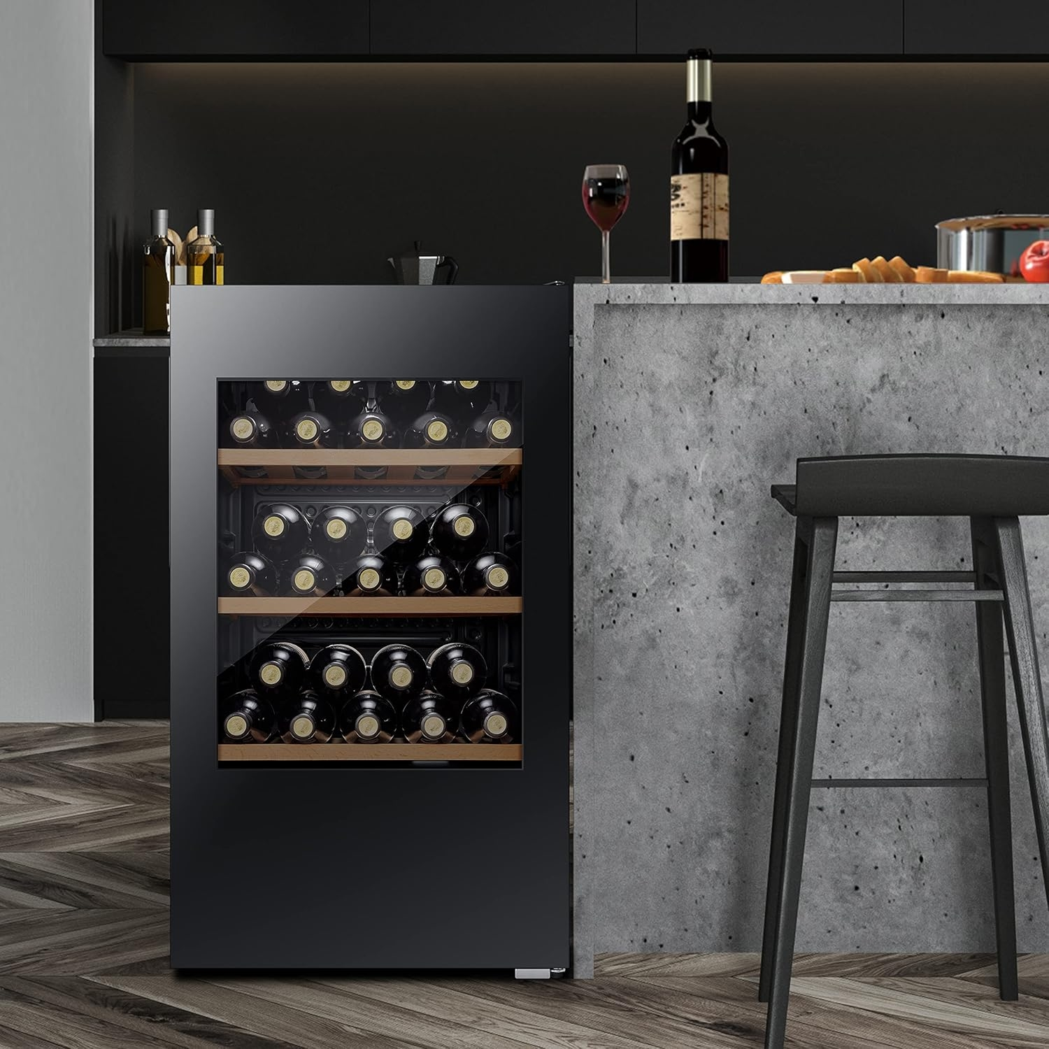 Un refrigeratore per vino nero pieno di bottiglie, una bottiglia di vino, un bicchiere da vino e uno sgabello in una cucina.