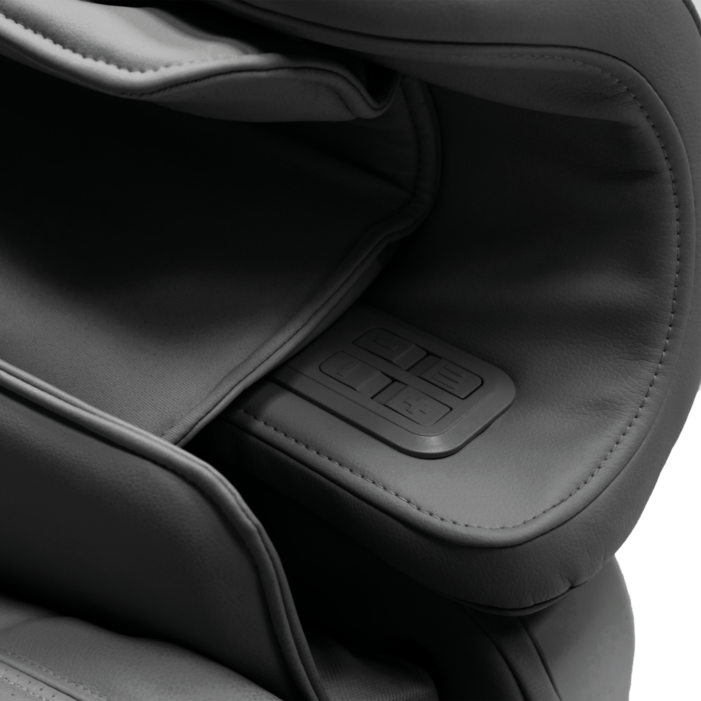 Close-up of a gray massage chair. Visible are the armrest, buttons, and cushions. The chair is in a monochrome style with a white background.