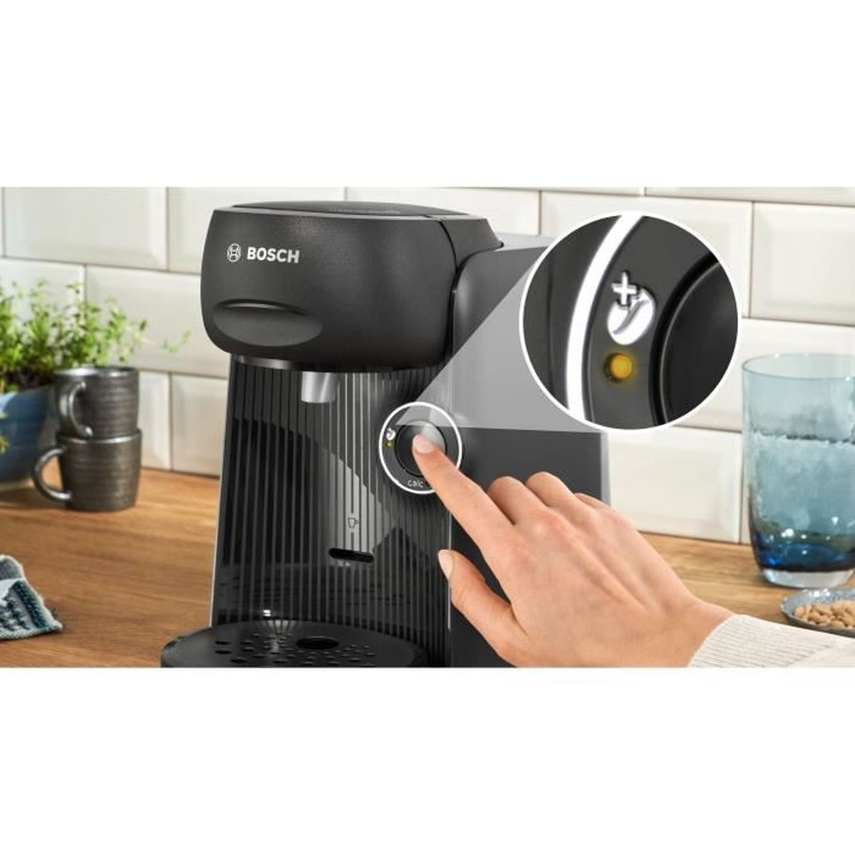 Ręka naciska przycisk na czarnym ekspresie do kawy. Ekspres ma logo Bosch. Powiększony widok pokazuje szczegóły przycisku.