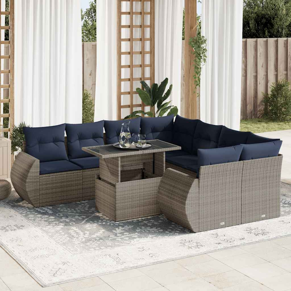 Outdoor-Ecksofa mit marineblauen Kissen, einem Couchtisch und einem Teppich auf einer Terrasse. Weiße Vorhänge und Pflanzen im Hintergrund.