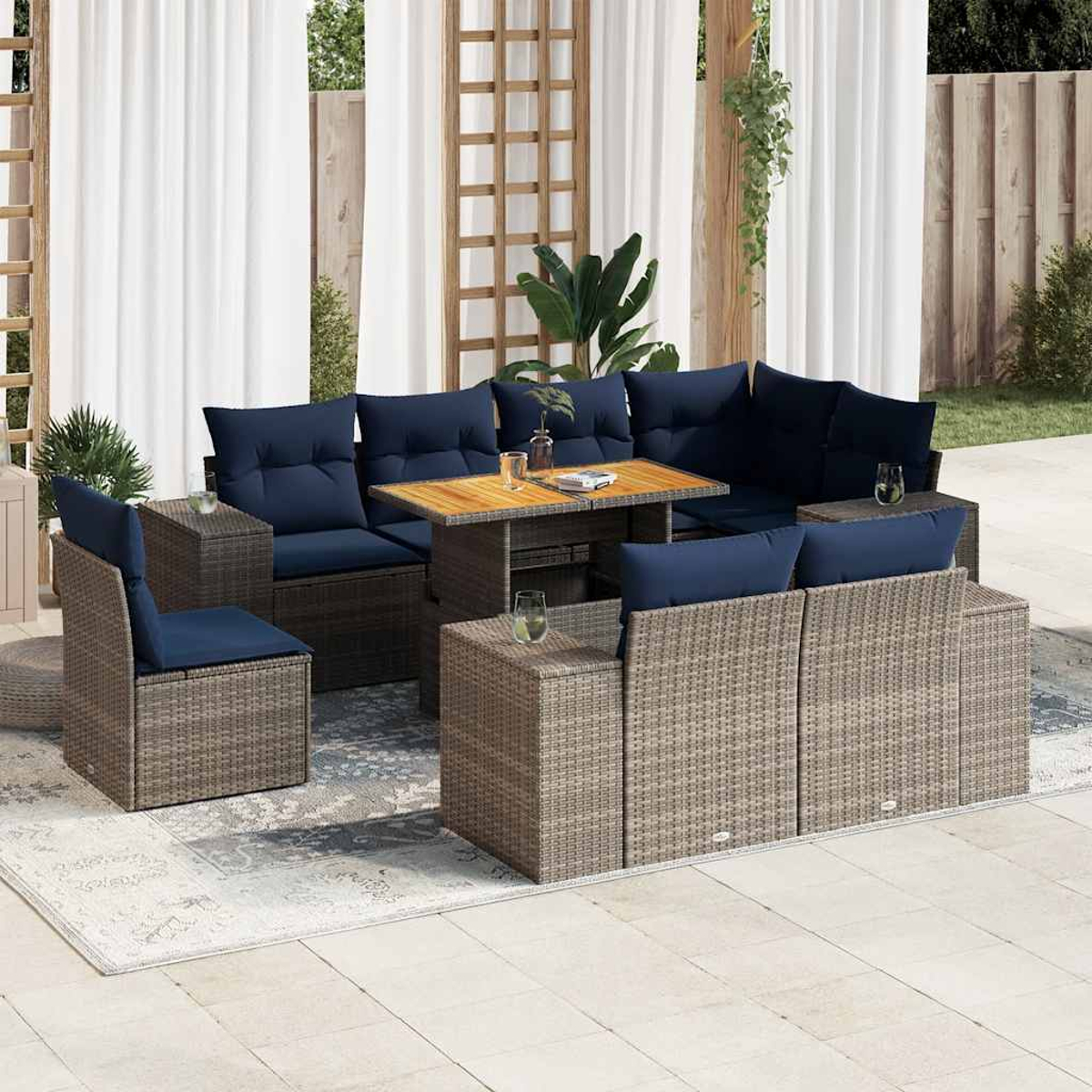 Juego de muebles de mimbre para exteriores con cojines azul marino, una mesa de madera y vasos. La escena está en un patio.