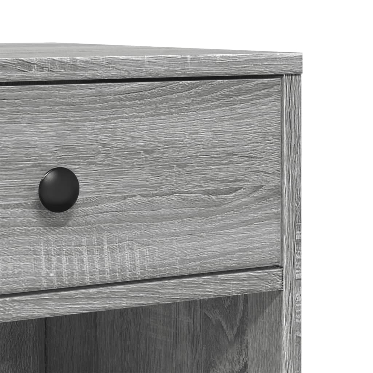 Nahaufnahme einer grauen Holzschublade mit einem schwarzen Knopf. Die Holzmaserung ist sichtbar. Teil eines Nachttischs aus Holz.
