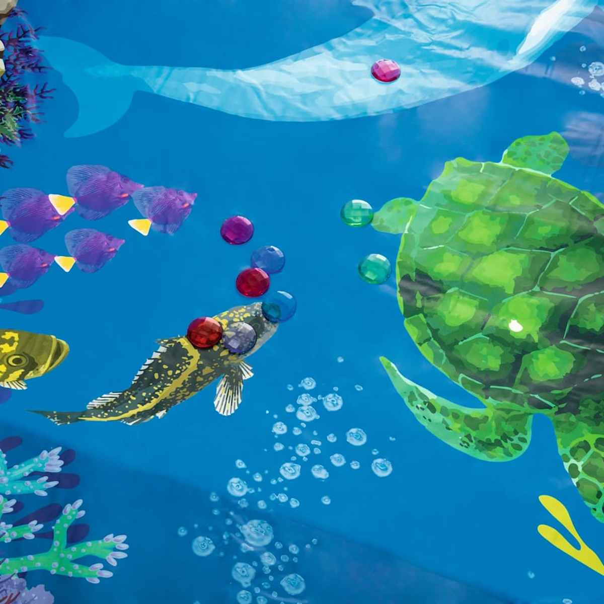 Unterwasserszene mit Fischen, Schildkröte, Wal und Blasen. Fische sind lila und gelb, Schildkröte ist grün. Blasen steigen auf.