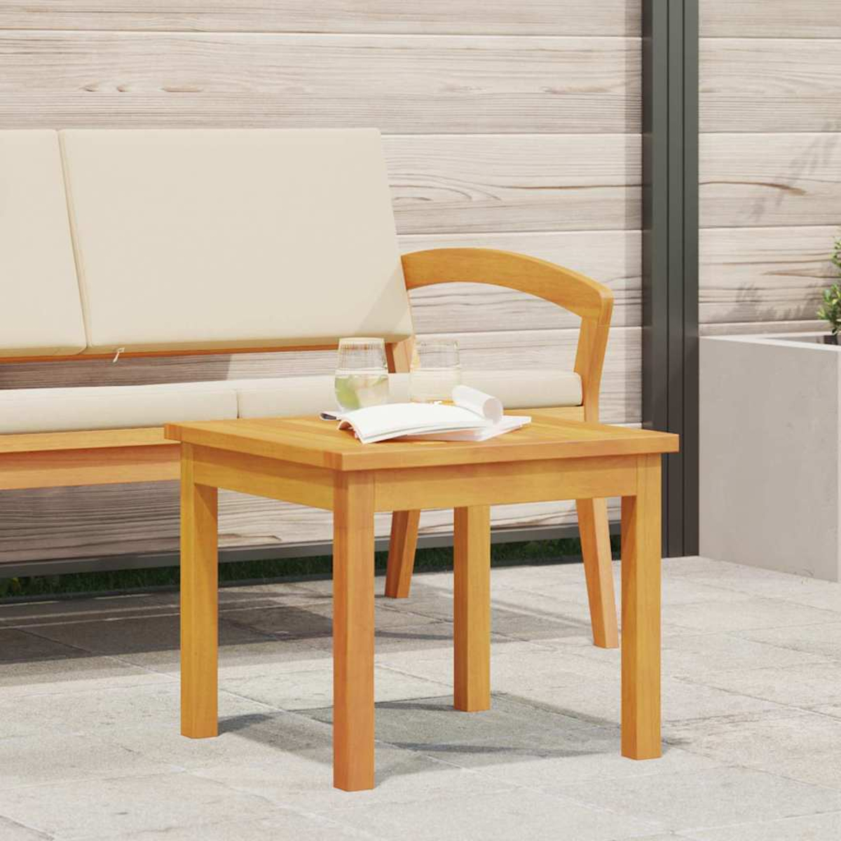 Escena exterior de madera con mesa, vasos y libro. Un sofá y una silla al fondo. El suelo es gris y la pared de madera.