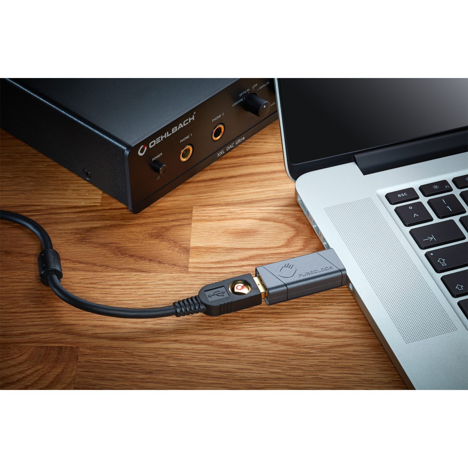 Ein Laptop ist über ein USB-Kabel mit einer schwarzen Audioschnittstelle verbunden. Hintergrund: Holztisch. Die Schnittstelle hat Kopfhöreranschlüsse.