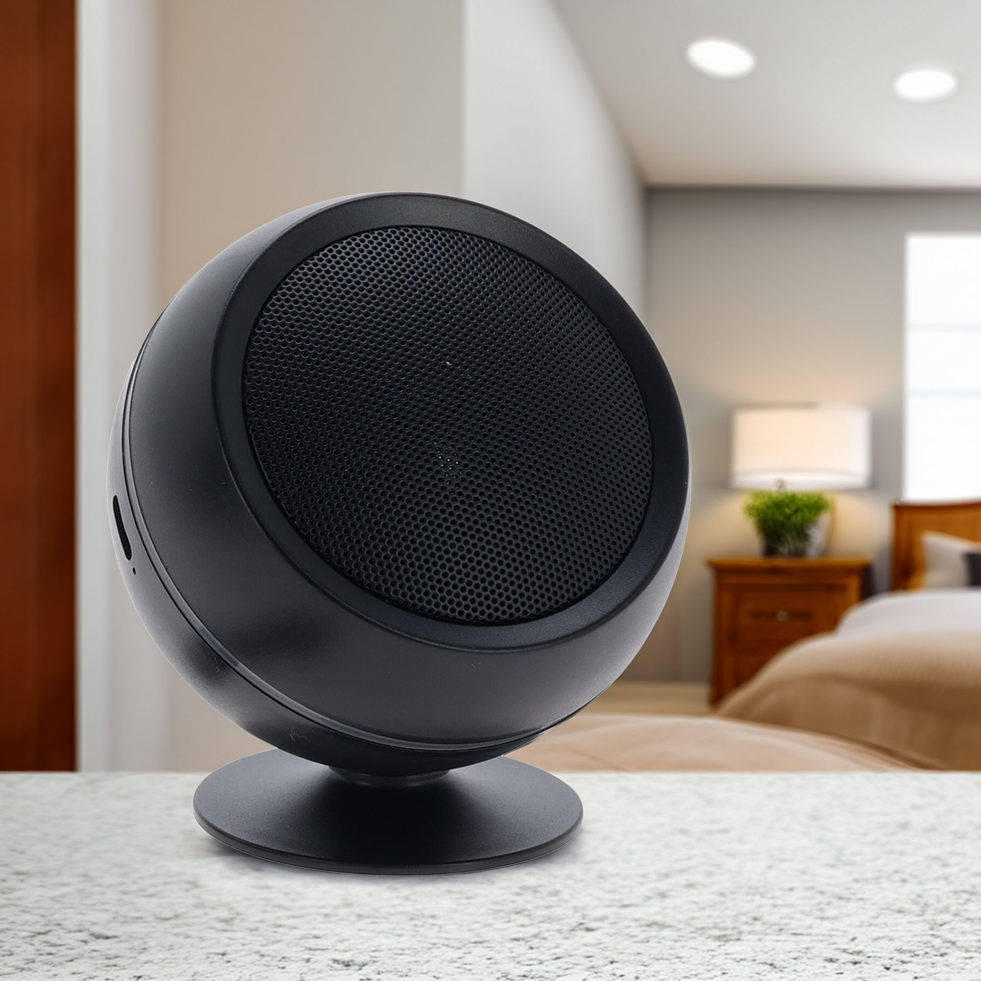 Un altavoz esférico negro sobre un soporte. Un dormitorio borroso está en el fondo con una cama y una lámpara.