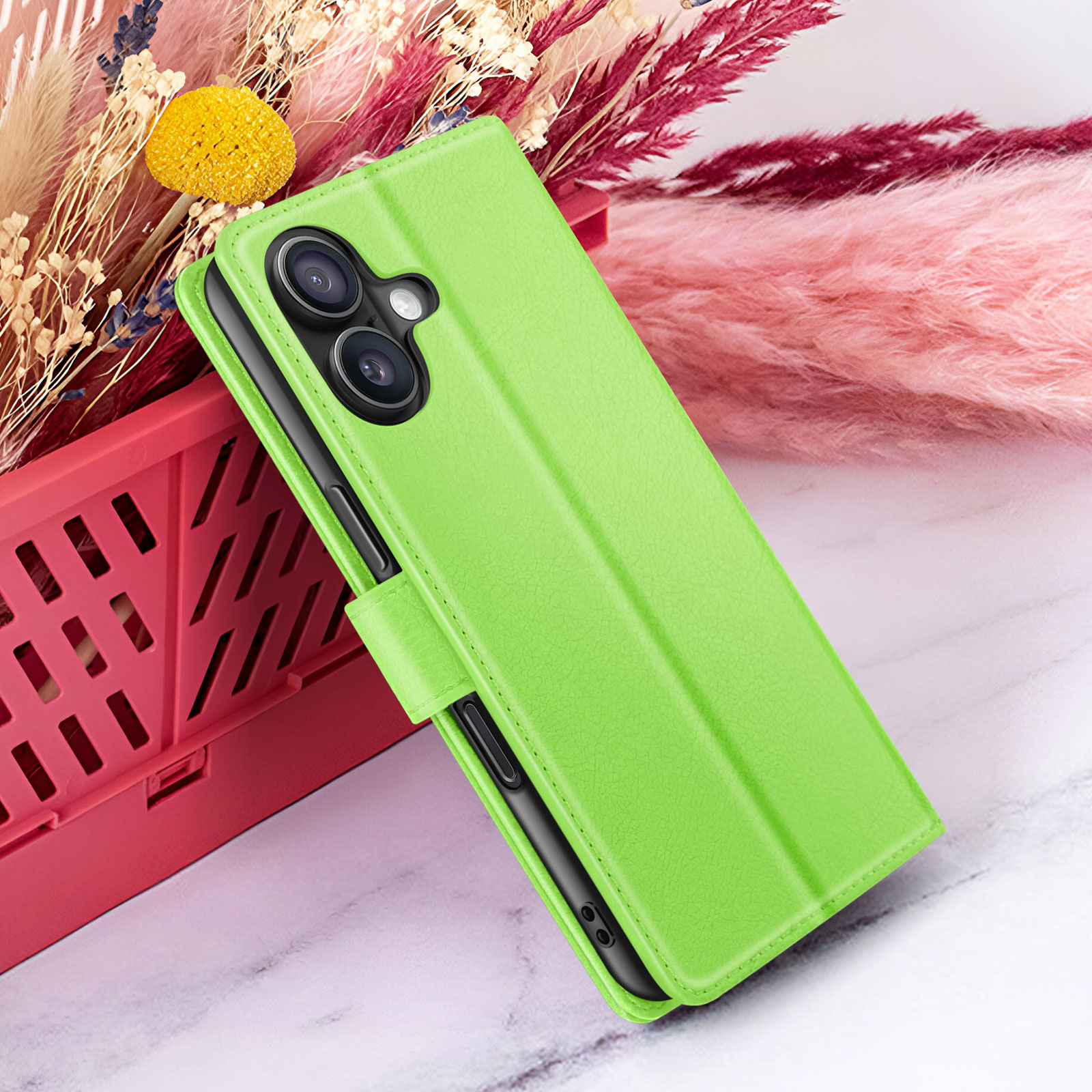Een limoengroene telefoonhoes is open en onthult de cameralenzen van de telefoon. Gedroogde bloemen op de achtergrond, op een marmeren oppervlak.