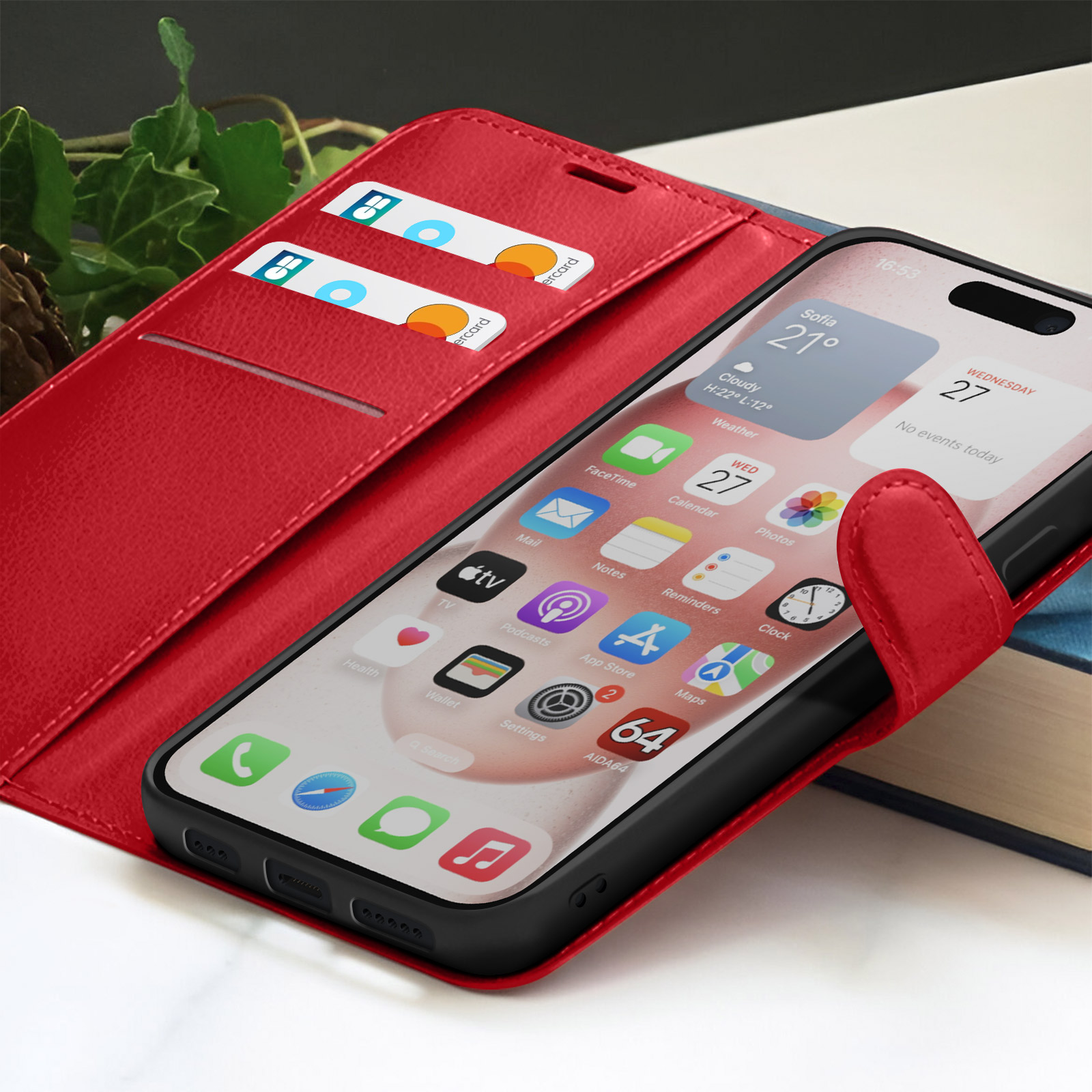 Rode telefoonhoes met smartphone met apps. Creditcards in de hoes. Een boek en groen op de achtergrond.