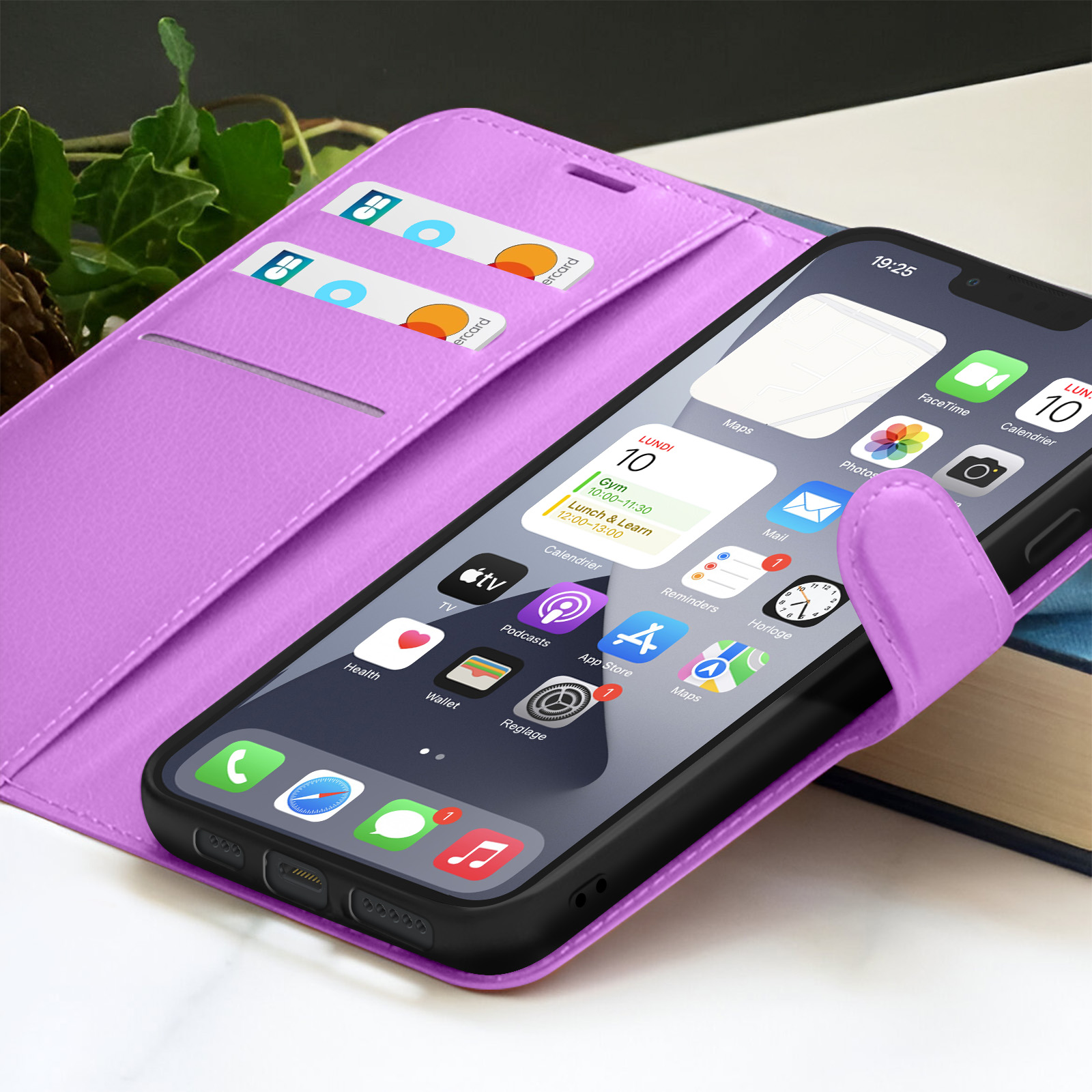 Un étui de téléphone violet contient un iPhone noir affichant des applications. Des cartes de crédit sont dans une fente. Fond avec des feuilles et un livre.