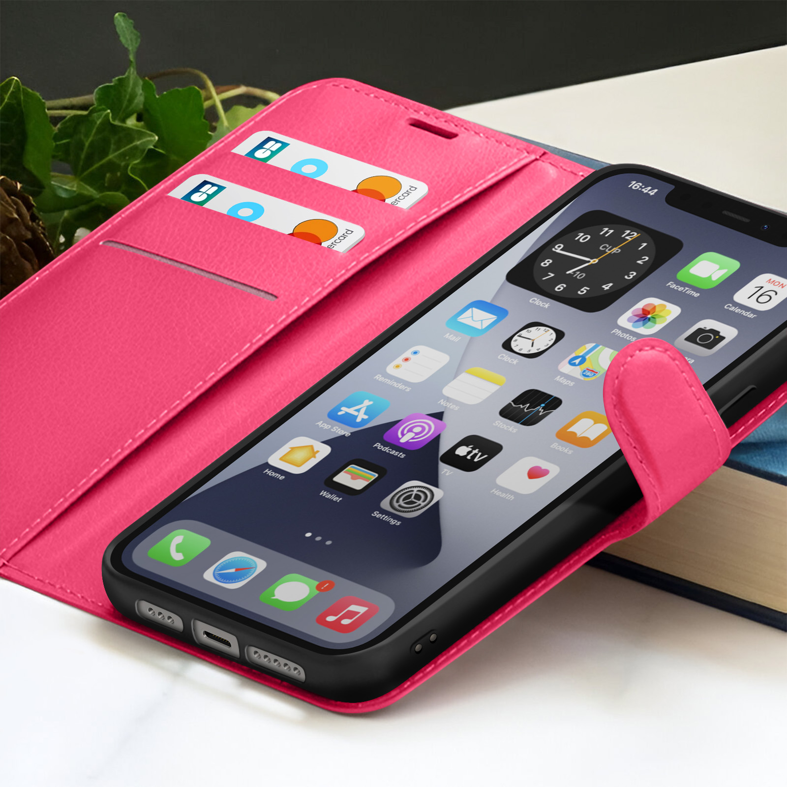 Een roze telefoonhoesje met een telefoon met pictogrammen. Creditcards zitten in de hoes. Een boek staat op de achtergrond.