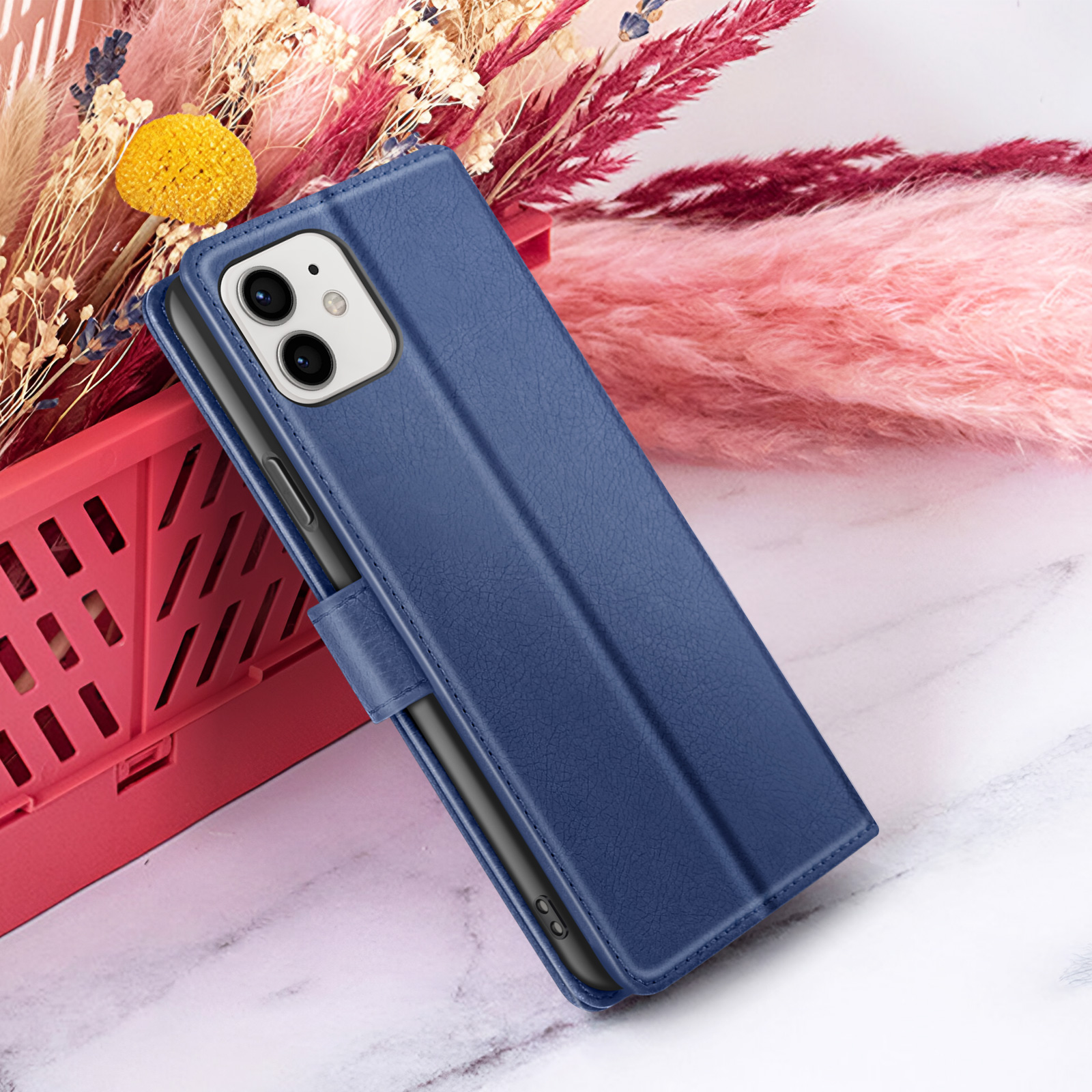Étui de téléphone bleu avec un téléphone à l'intérieur, devant des fleurs roses et blanches avec un panier rouge à gauche.