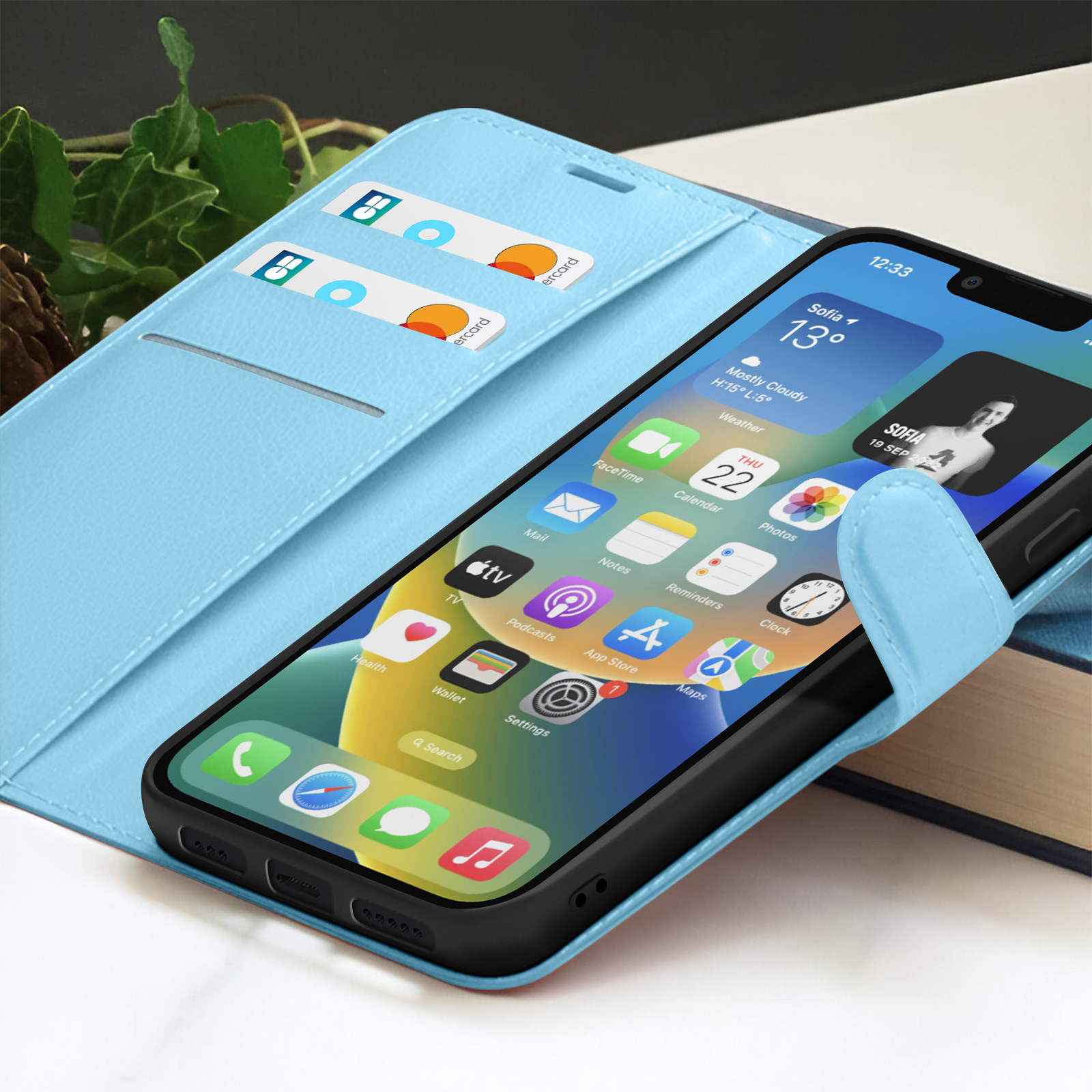Een smartphone in een lichtblauwe hoes, met het startscherm met apps. Twee creditcards zijn zichtbaar in de hoes.