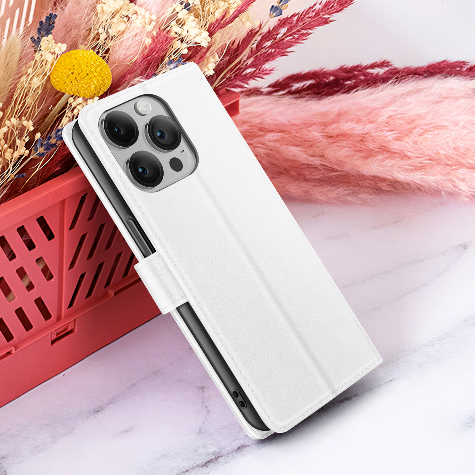 Coque de téléphone blanche sur marbre, avec des fleurs séchées et un panier rouge en fond.