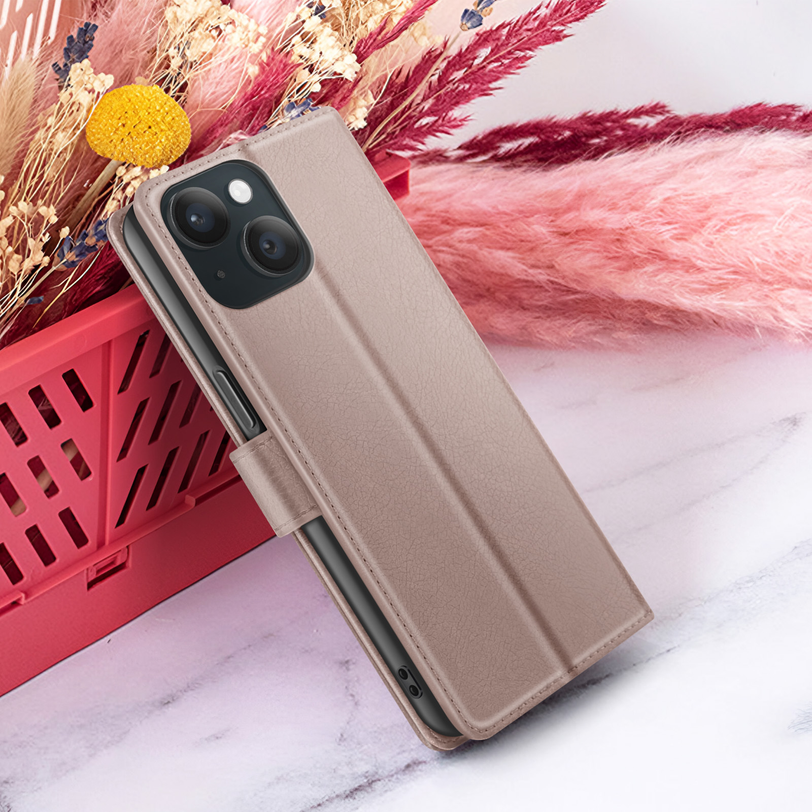 Un étui de téléphone de couleur beige est présenté, avec un téléphone à l'intérieur. Le fond a des fleurs et une surface en marbre.