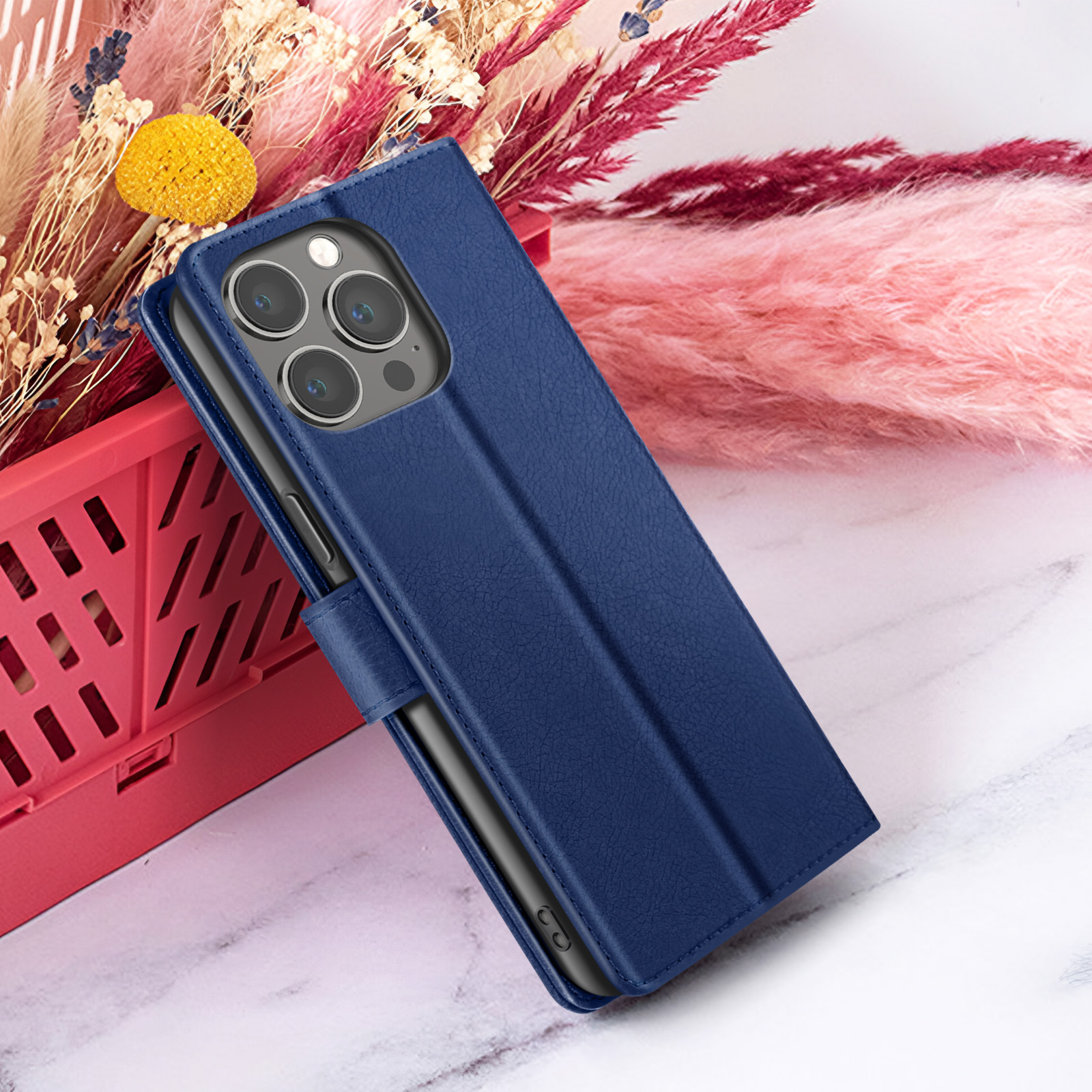 Een marineblauwe telefoonhoes met meerdere cameralenzen, rustend op een marmeren oppervlak met bloemdecoraties.