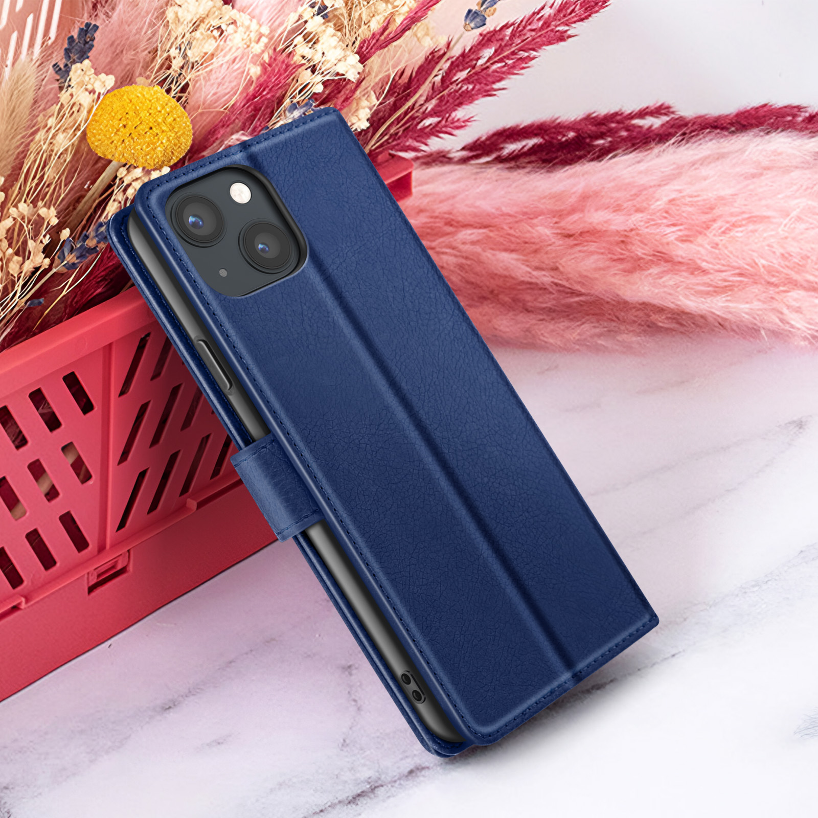 Een blauwe telefoonhoes met een telefoon erin. Achtergrond heeft roze en beige bloemen.